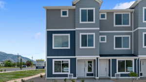 Modern townhouse exterior featuring a multi-tone facade with dark blue vertical siding, light blue horizontal siding, and grey stucco accents