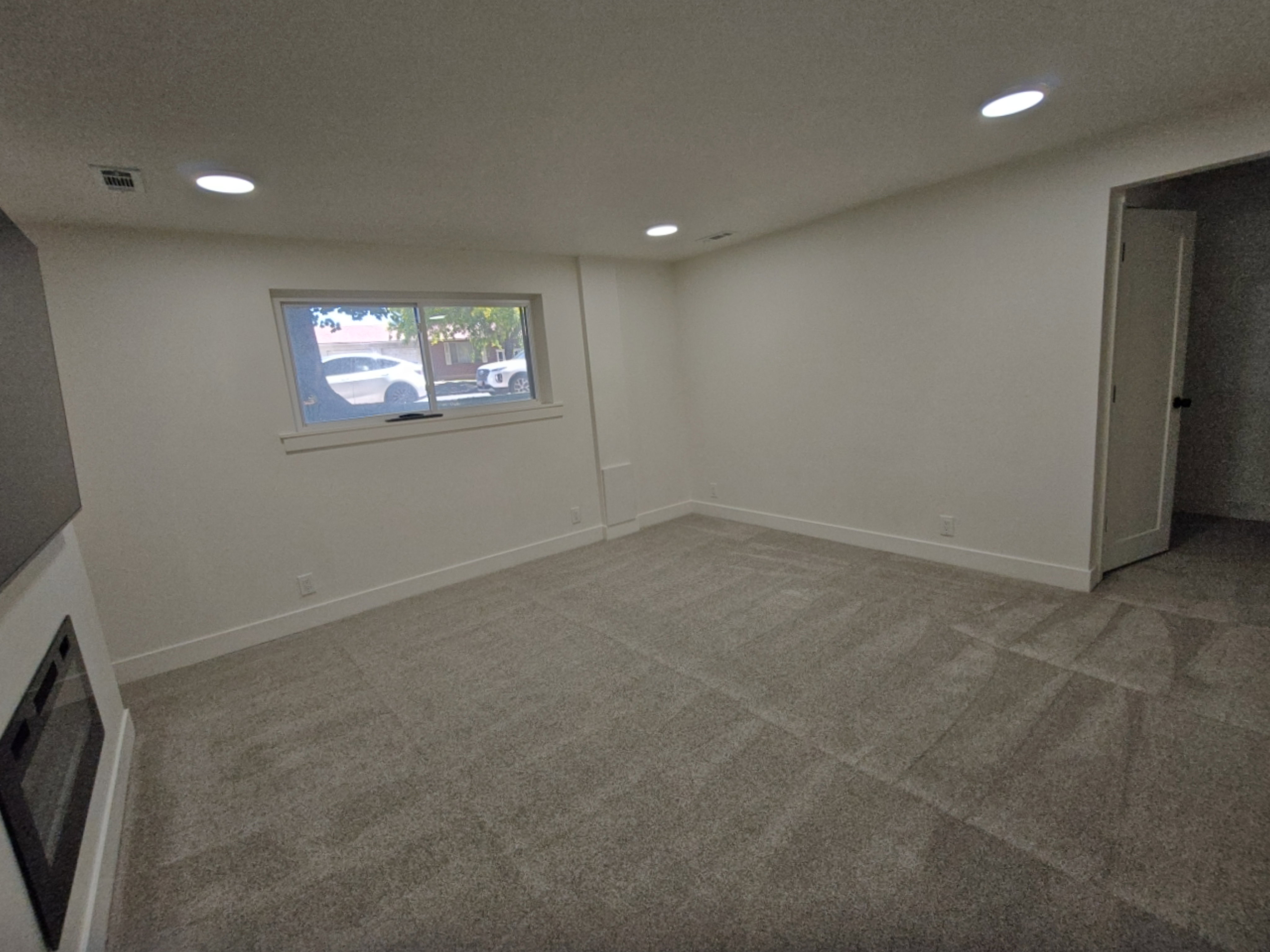 Spacious room featuring neutral carpet, white walls, recessed lighting, and a modern built-in fireplace