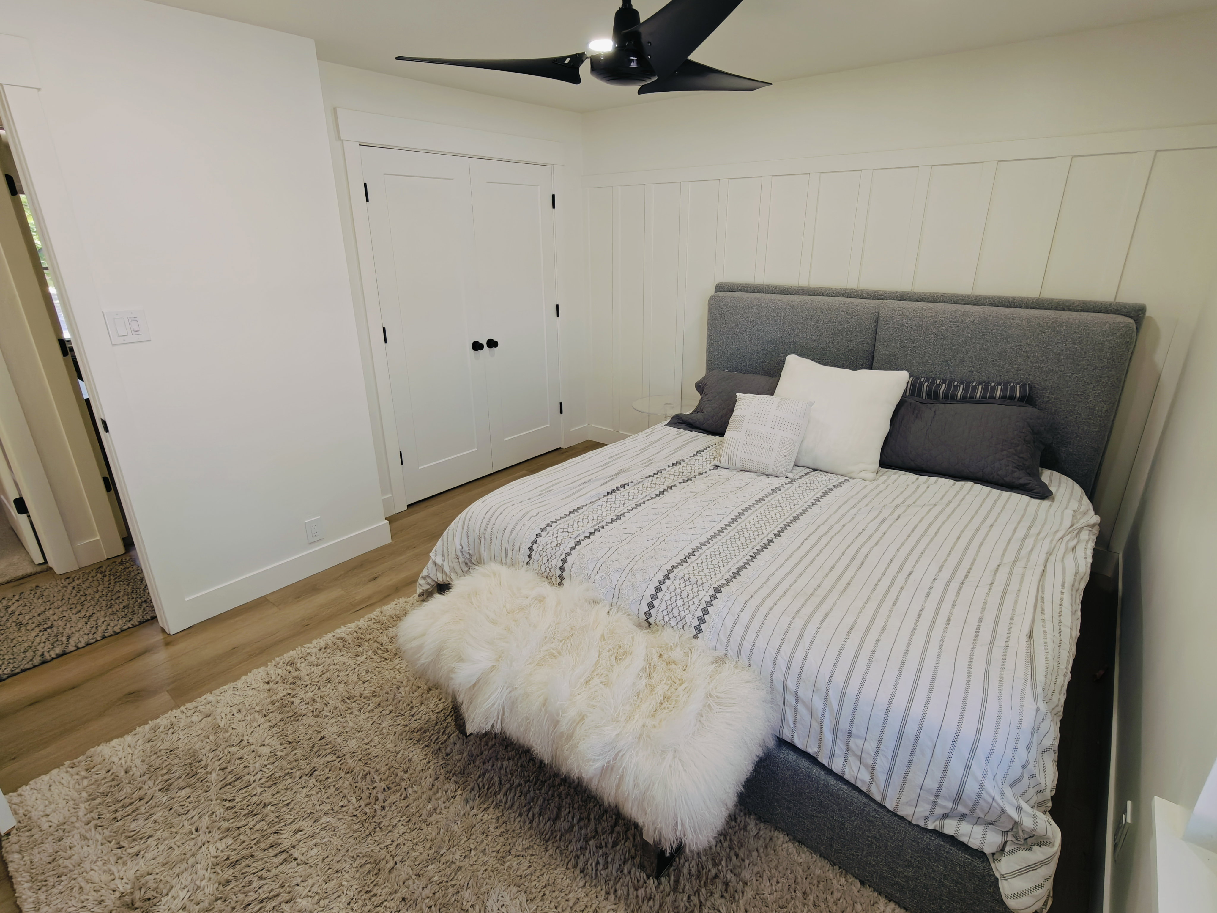 Bedroom featuring wood-finish flooring, a contemporary ceiling fan, and white paneled walls