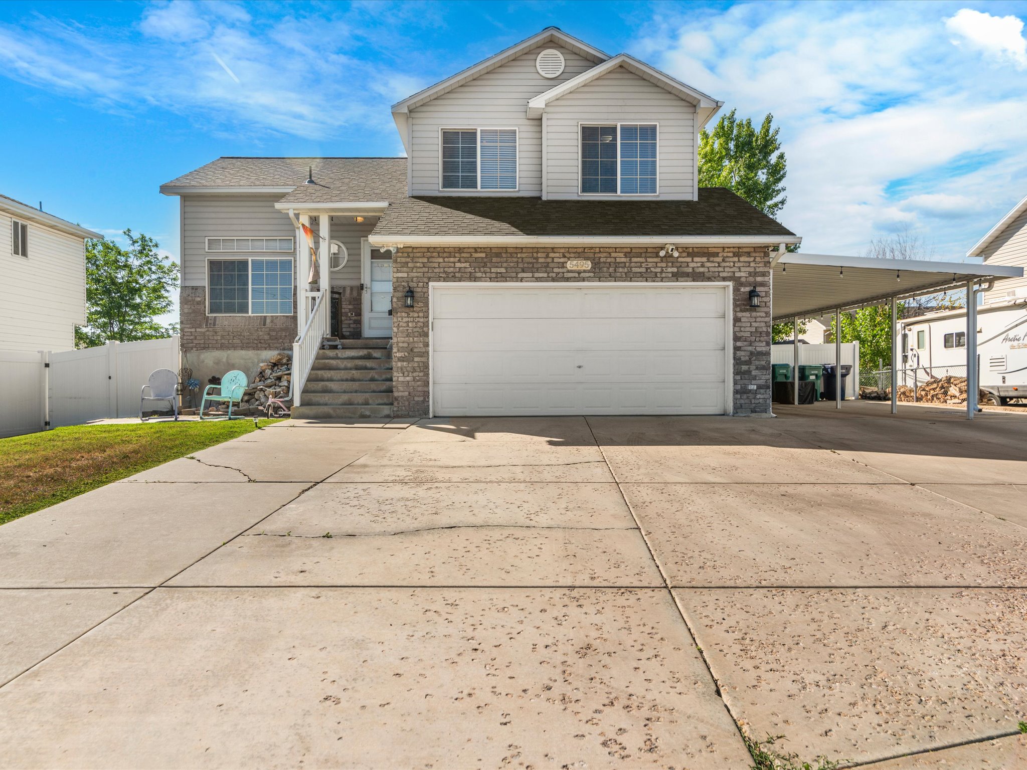 Two-story residence featuring a two-car garage, brick facade detailing, and a covered side carport