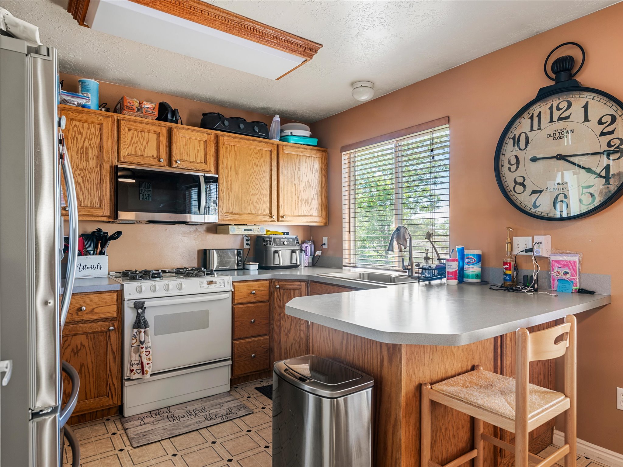 Kitchen with wood-finish cabinetry, light-toned countertops, and a built-in stainless steel microwave