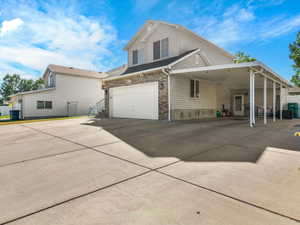 Two-story property featuring a stone and siding exterior, an attached two-car garage, and a covered carport