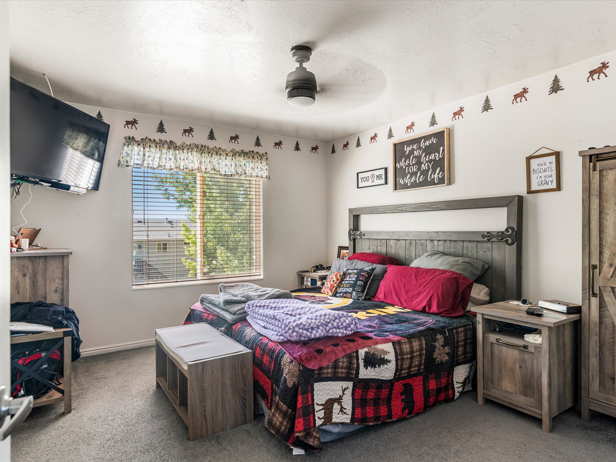 Carpeted bedroom featuring a window with horizontal blinds, a ceiling fan, and light-toned walls