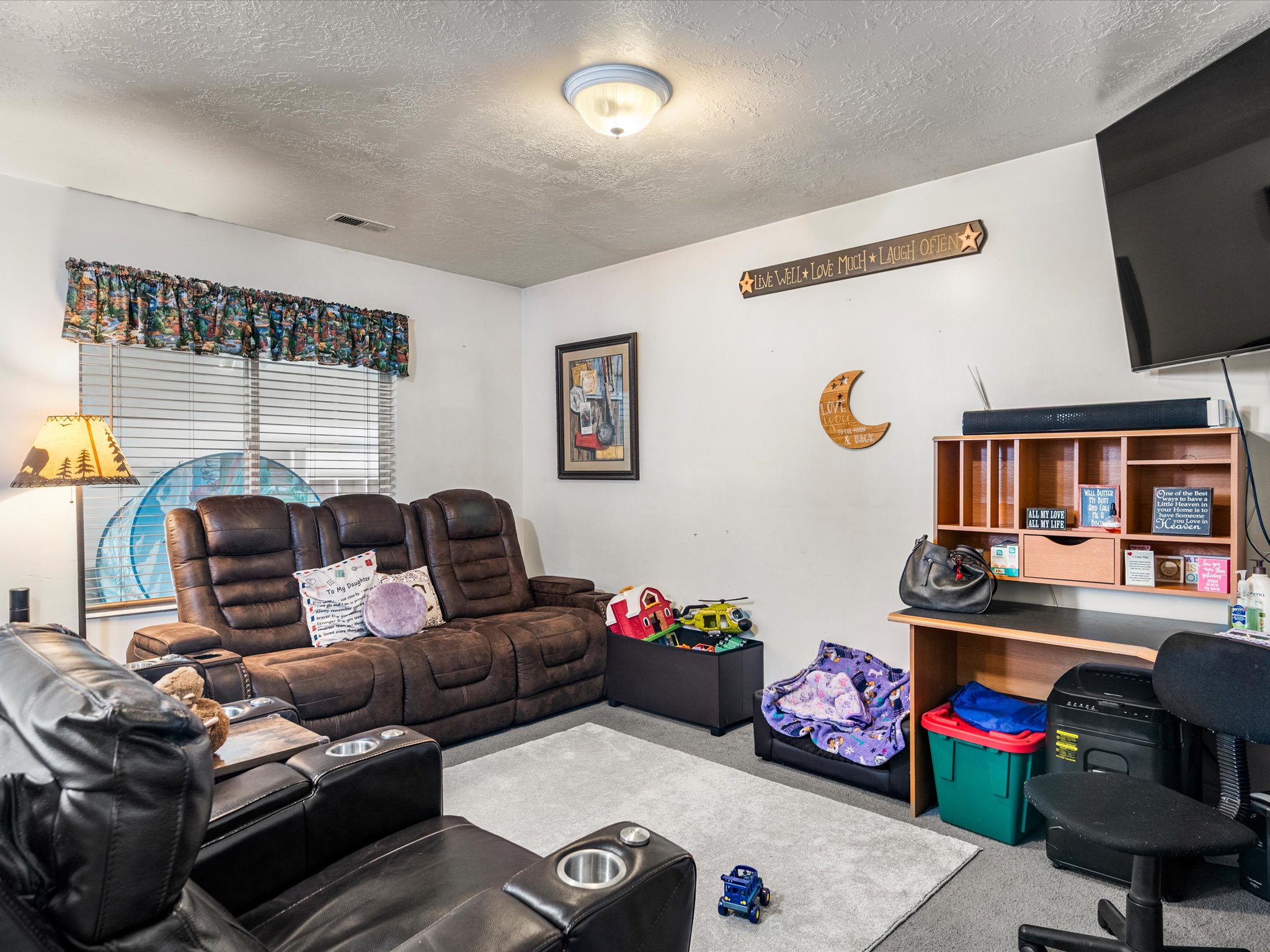 Carpeted room with a ceiling-mounted light fixture, white walls, and a window with horizontal blinds