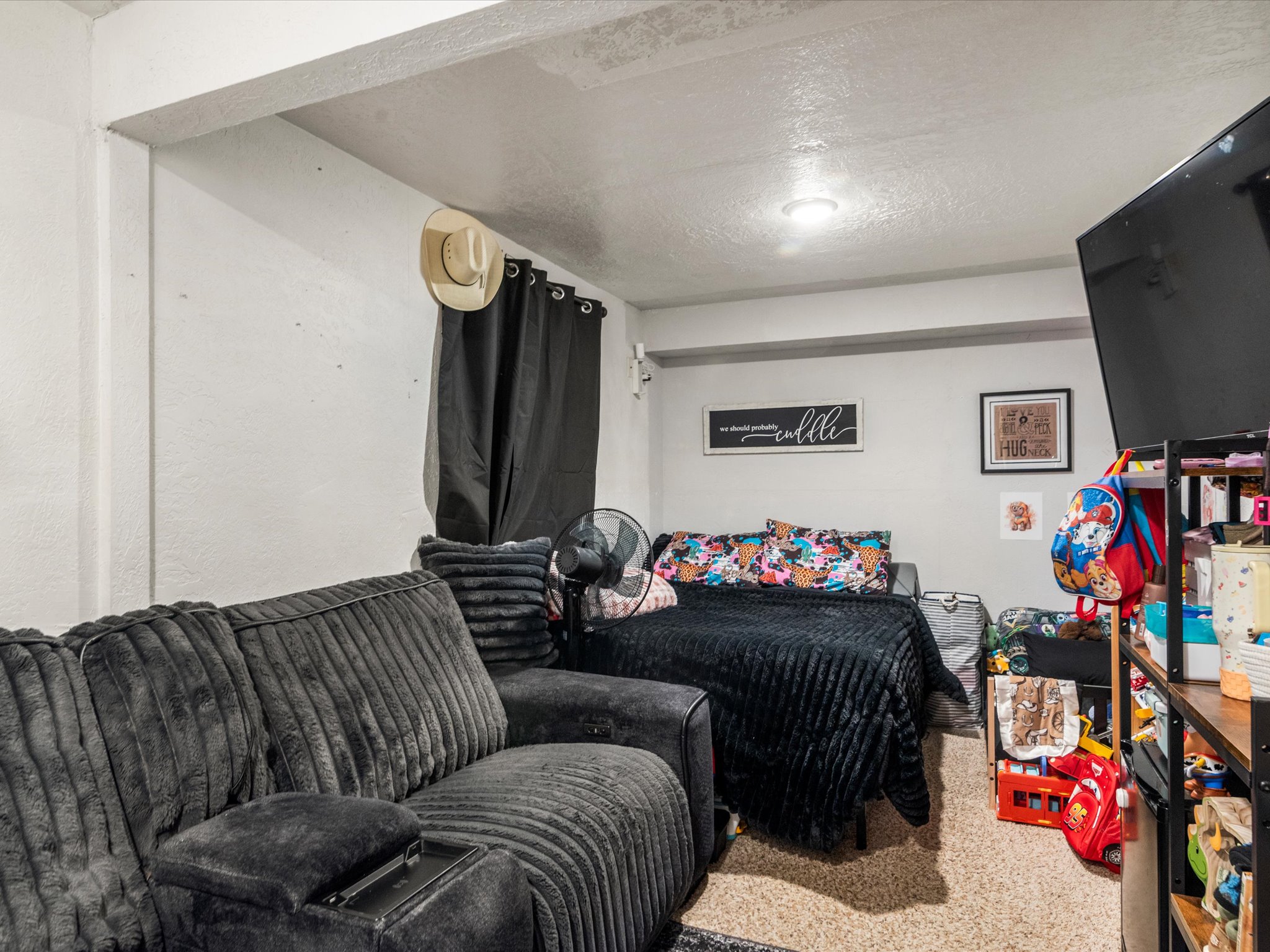 Carpeted room with a recessed ceiling light and a window with black curtains