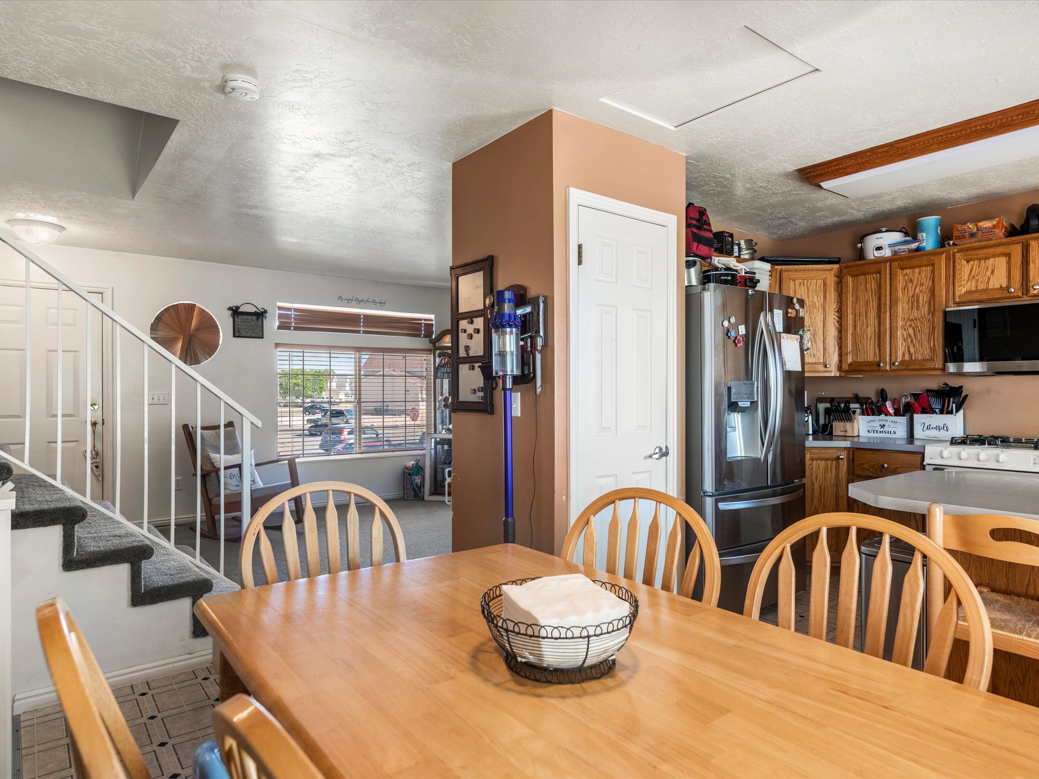 Open concept dining area with wood-finish flooring, featuring a kitchen with wood cabinetry and stainless steel appliances