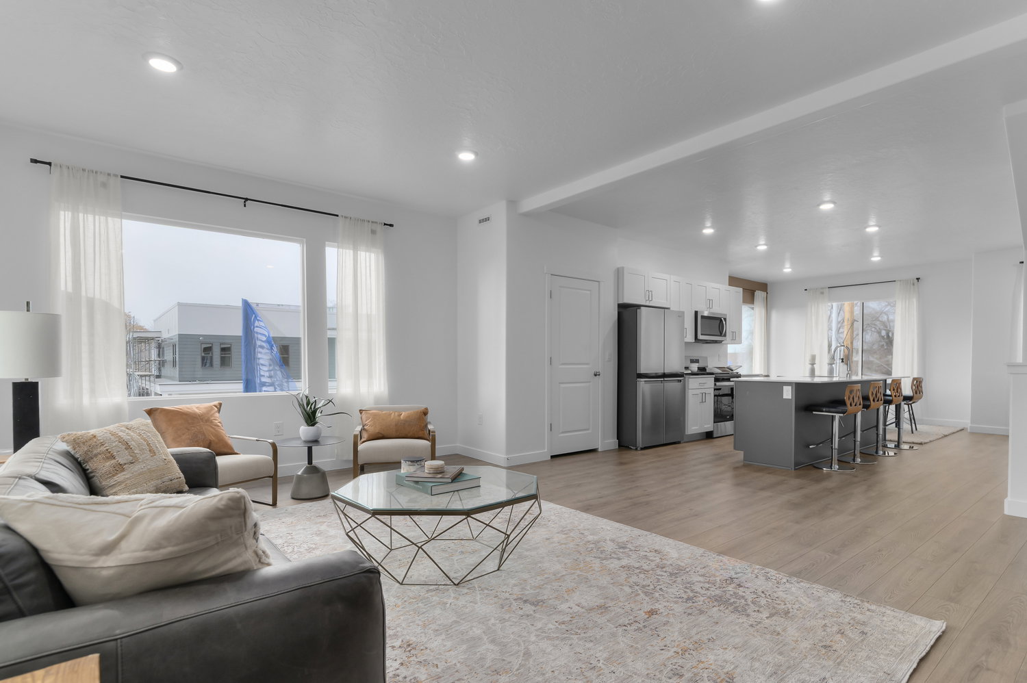 Open-concept living space featuring wood-finish flooring, recessed lighting, and a large picture window