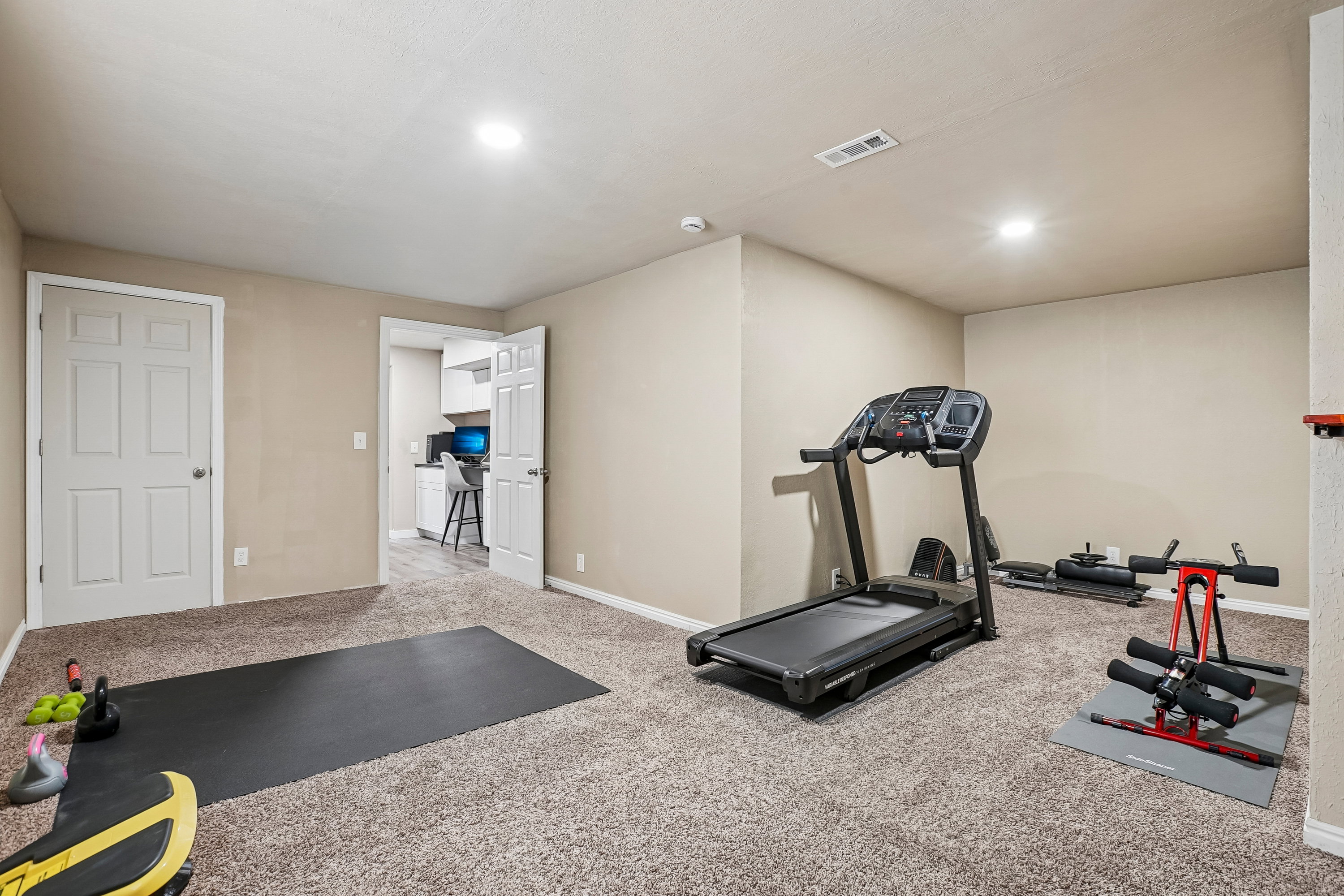 Versatile room featuring plush carpeting, neutral wall tones, recessed lighting, and a white six-panel door