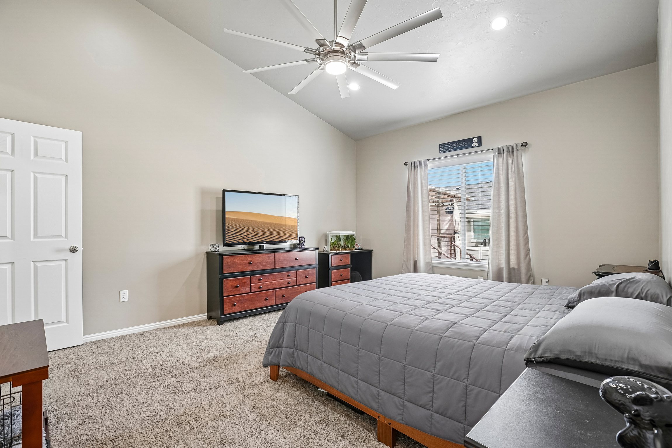 Vaulted ceilings featuring a ceiling fan with integrated lighting, a window with horizontal blinds and drapery rods, and neutral-toned wall paint