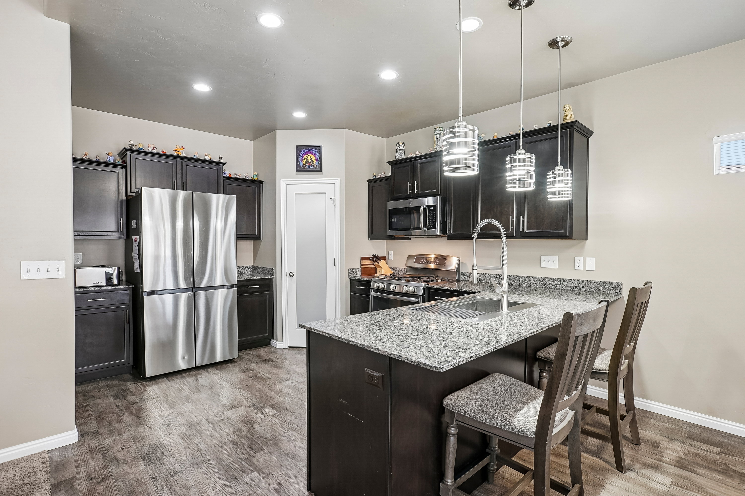 Kitchen featuring dark wood cabinetry, stainless steel appliances, and a central island with a granite countertop