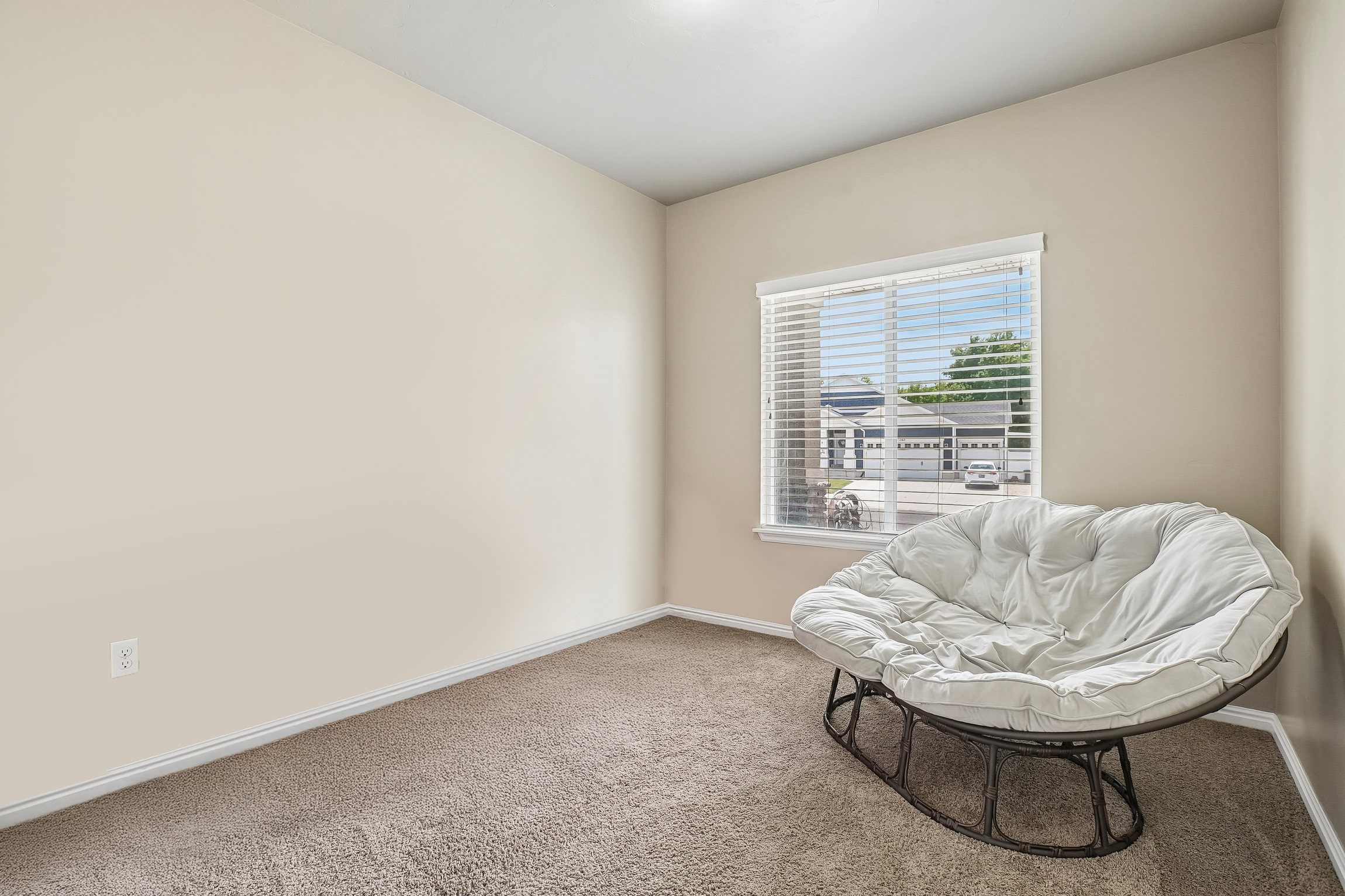 Carpeted room with a white window frame, horizontal blinds, and neutral-toned walls