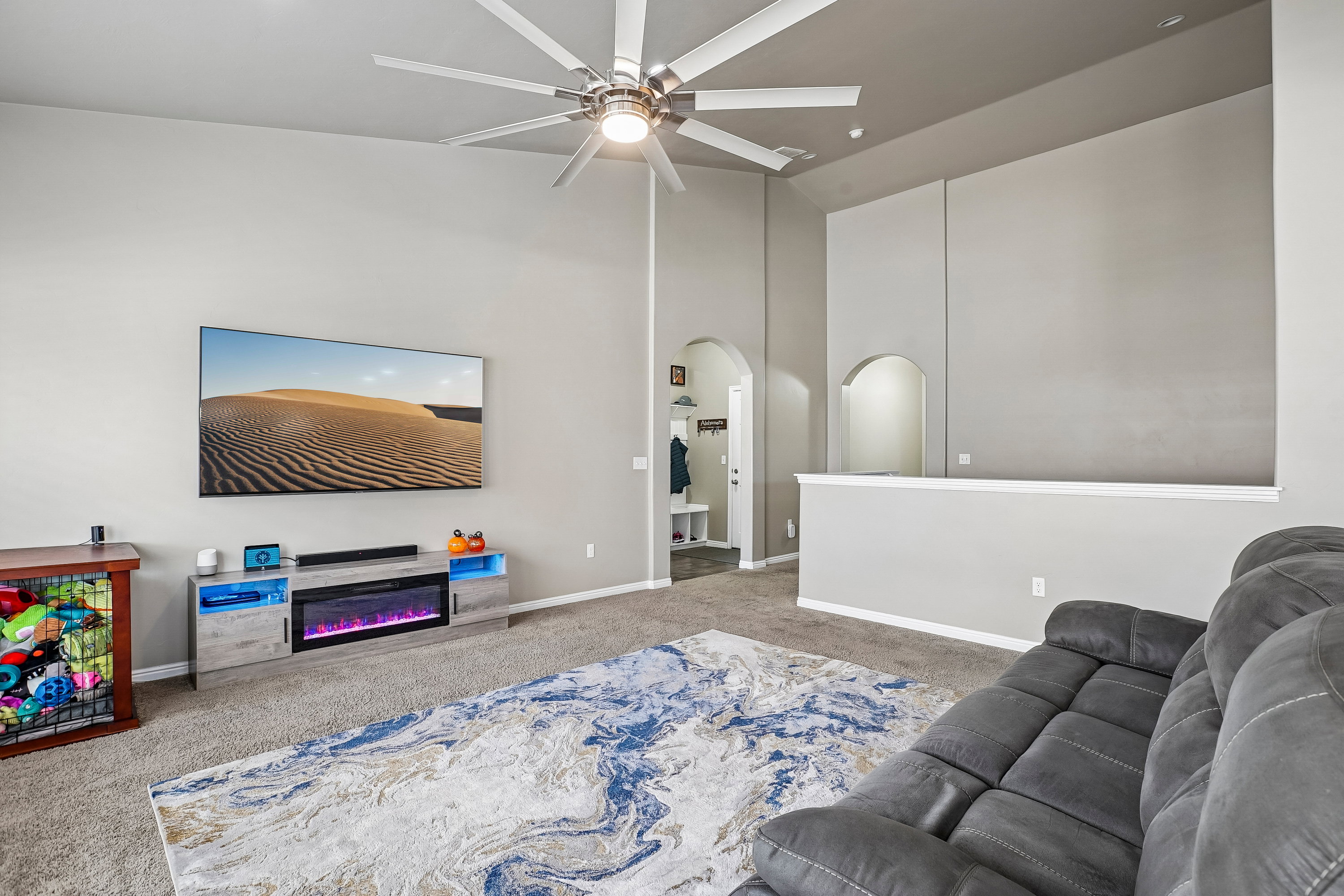 Spacious living area featuring vaulted ceilings, a contemporary ceiling fan, and light gray wall tones