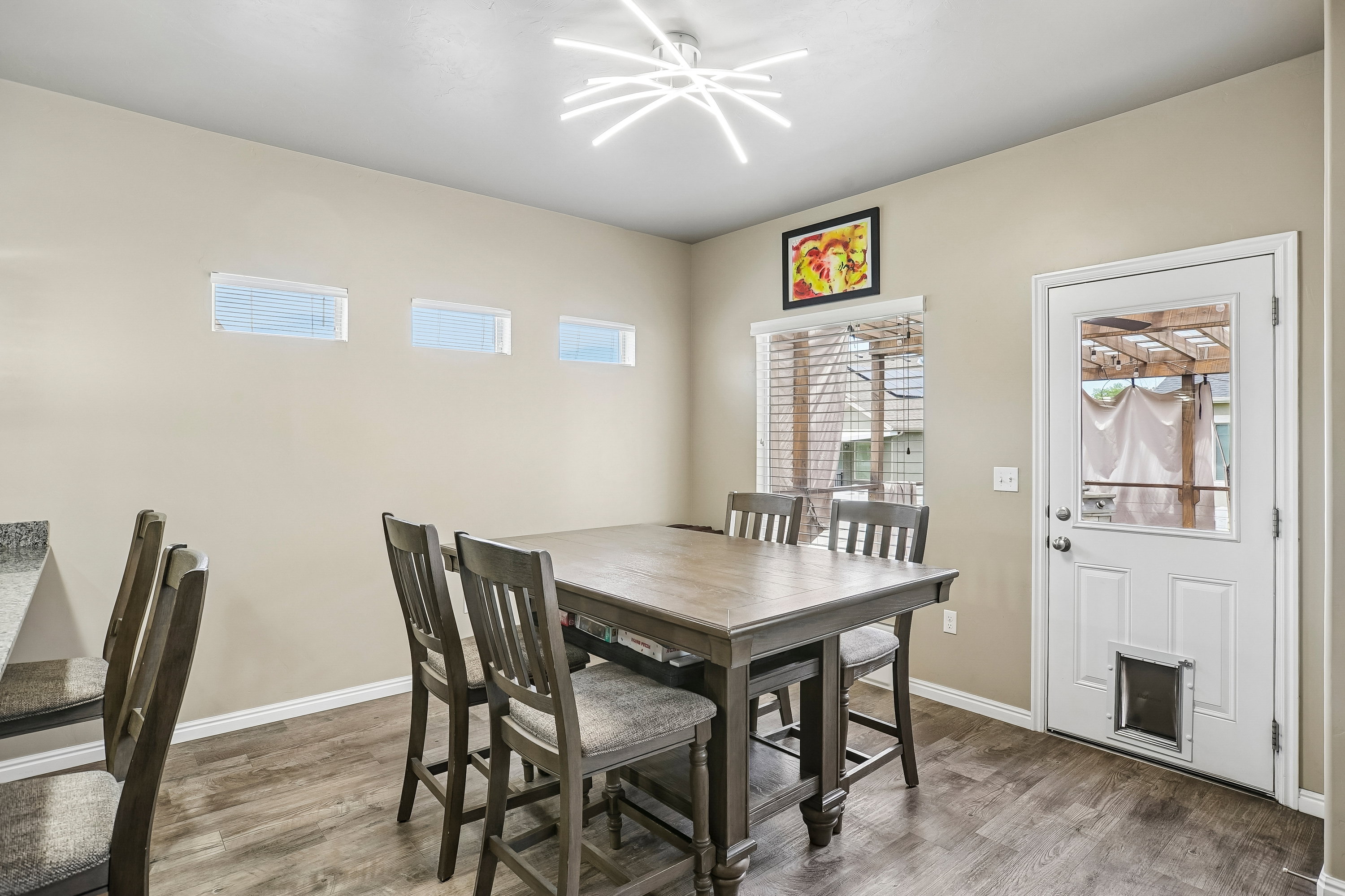 Dining area featuring wood-finish flooring, a contemporary light fixture, and a glass-paned exterior door