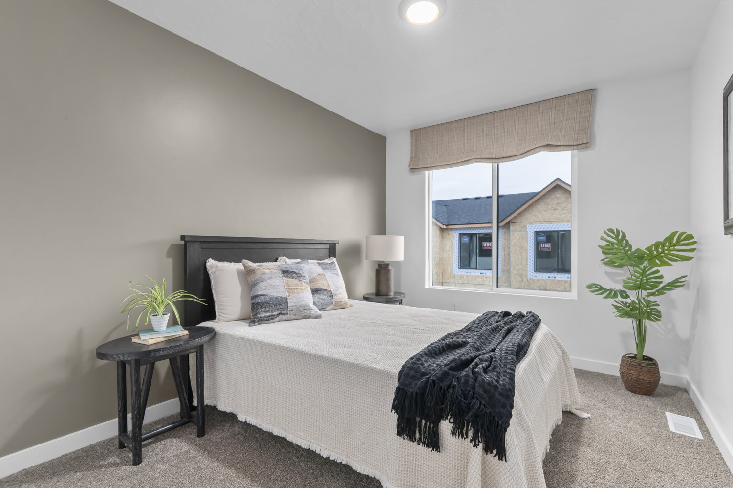 Bedroom featuring neutral-toned walls, recessed lighting, and a large window with a Roman shade