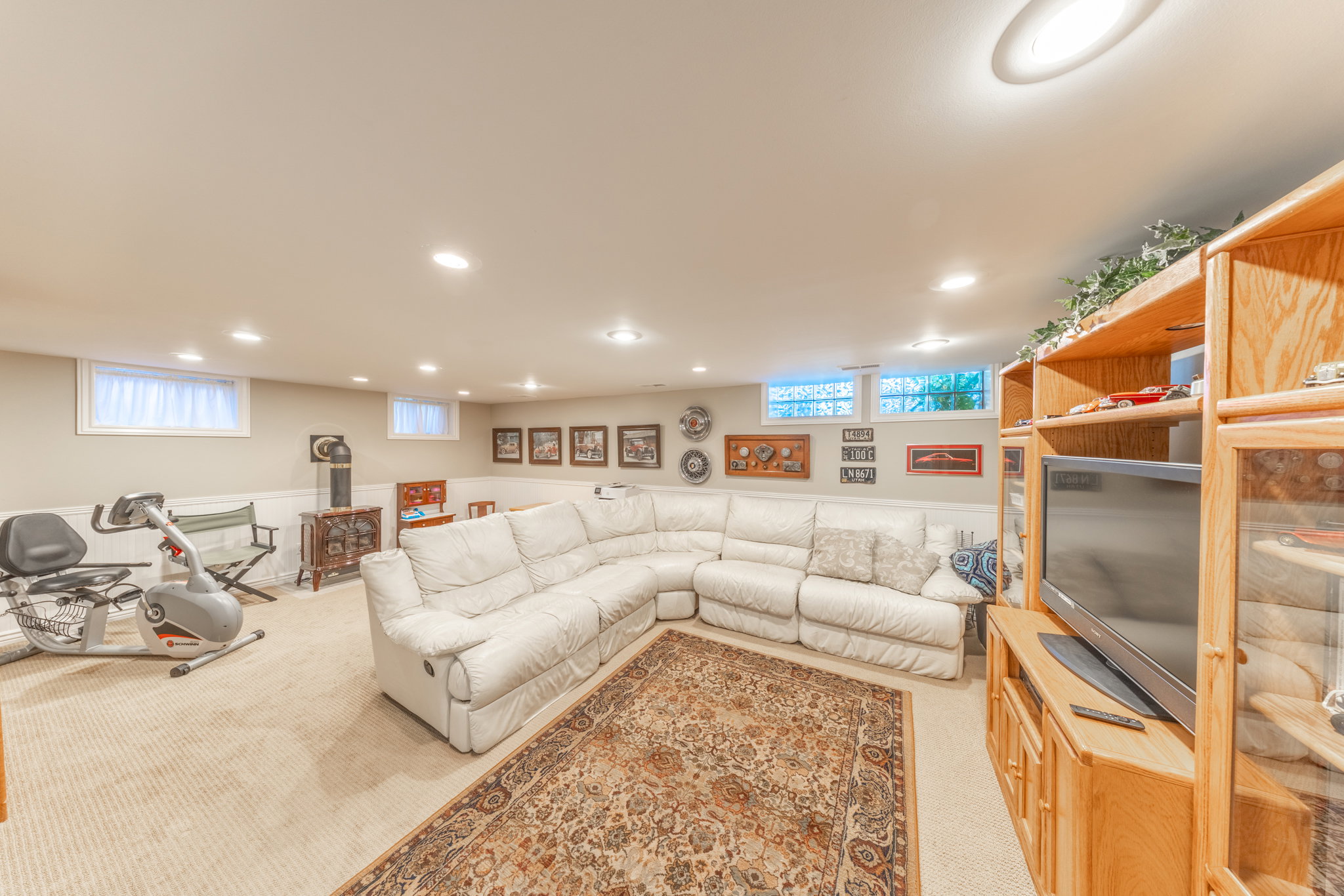Lower level featuring recessed lighting, light beige carpeting, white wainscoting, and a built-in wood-finish entertainment center