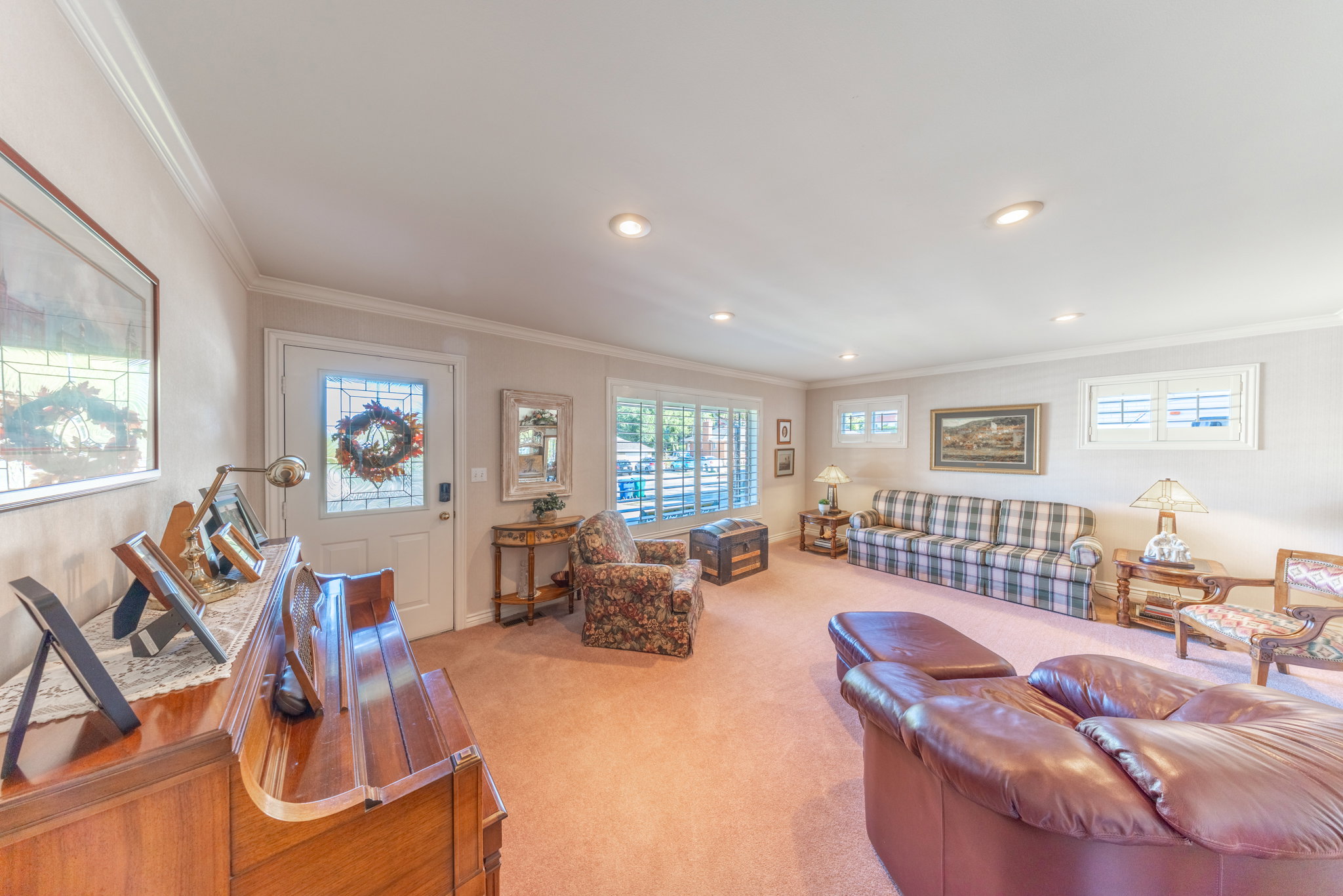 Carpeted living area featuring recessed lighting, crown molding, and multiple windows with white louvered shutters