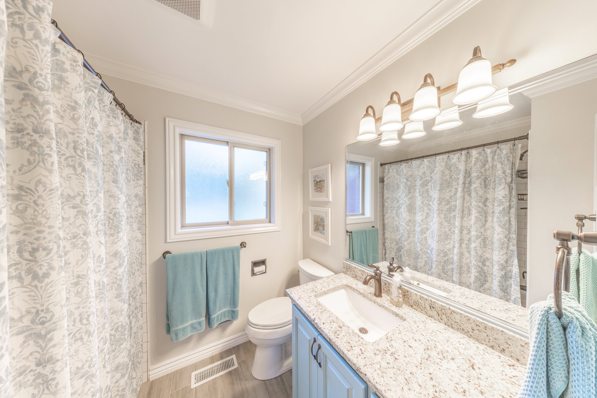 Bathroom featuring a vanity with granite-style countertop, a single basin sink, and light blue cabinetry