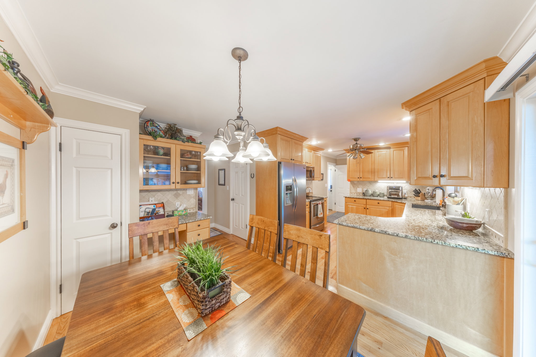 Dining area with a wood-finish table, featuring a chandelier, crown molding, and wood-finish flooring