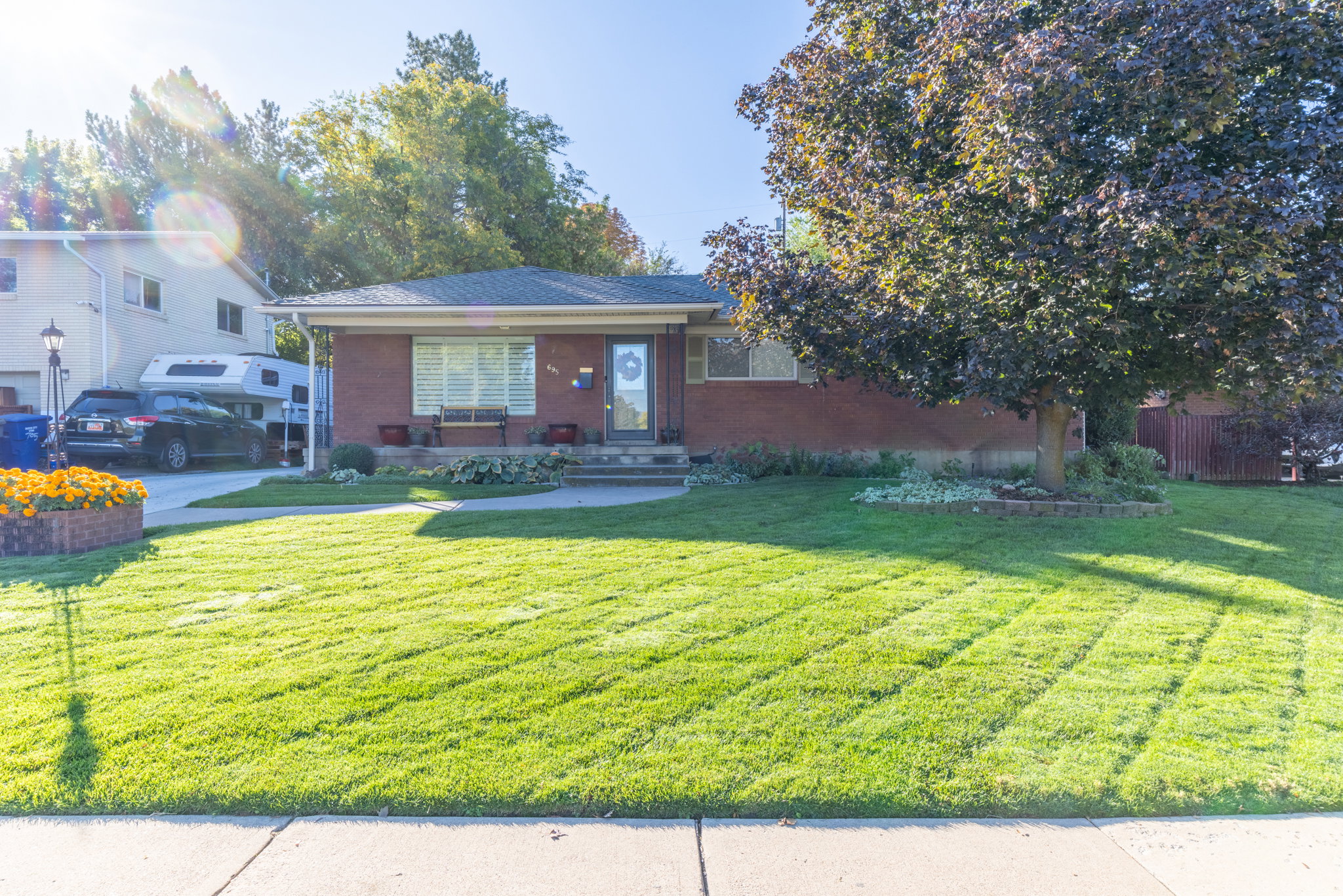 Brick residence with a mature front yard tree and a manicured lawn