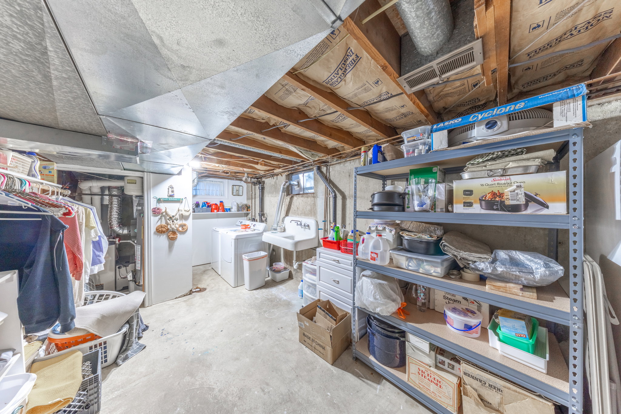 Basement utility area featuring a washer and dryer, a utility sink, and exposed ceiling joists