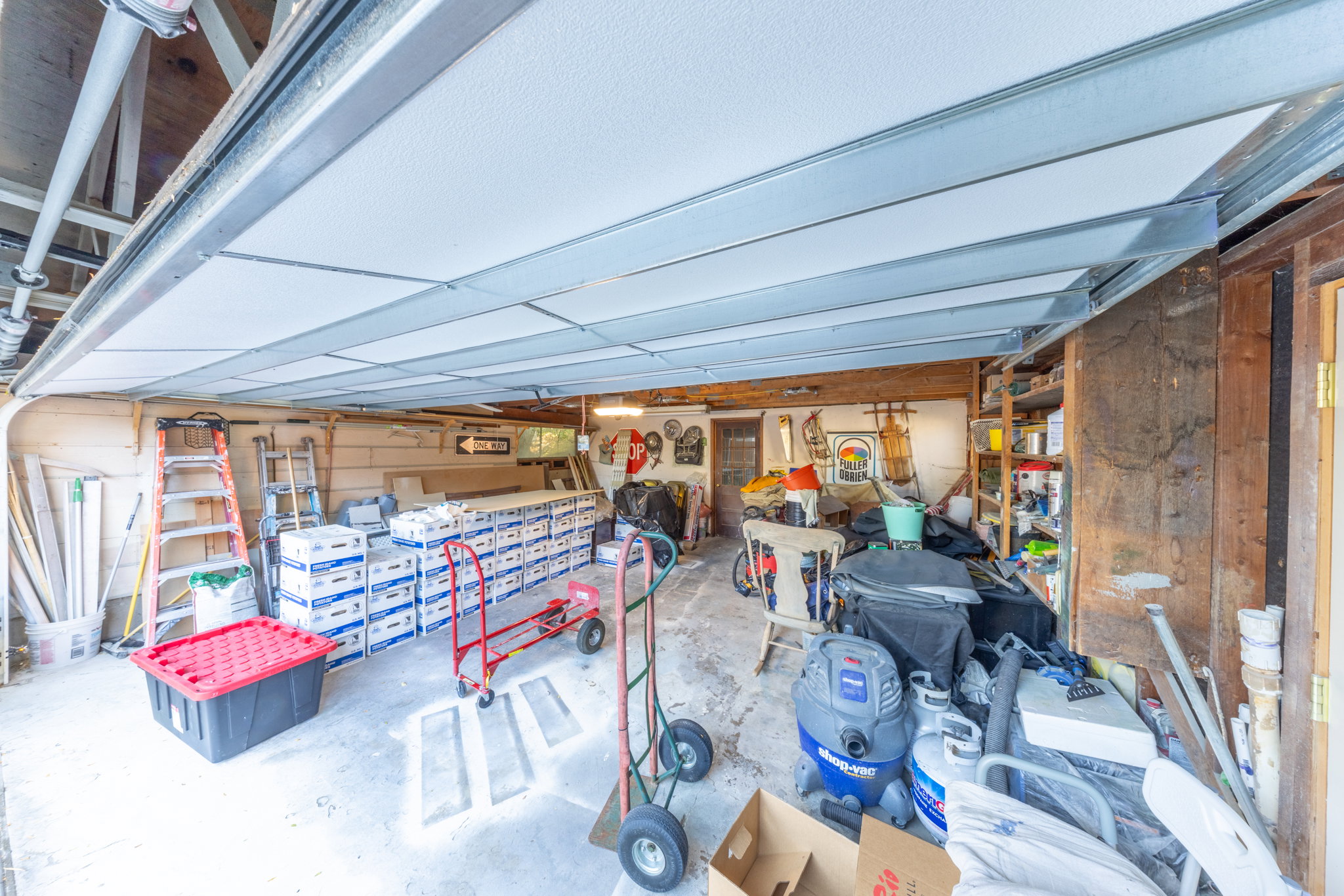 Garage interior featuring a concrete floor, exposed wooden beams, and built-in shelving