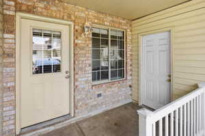 Entryway featuring brick veneer and light-toned siding