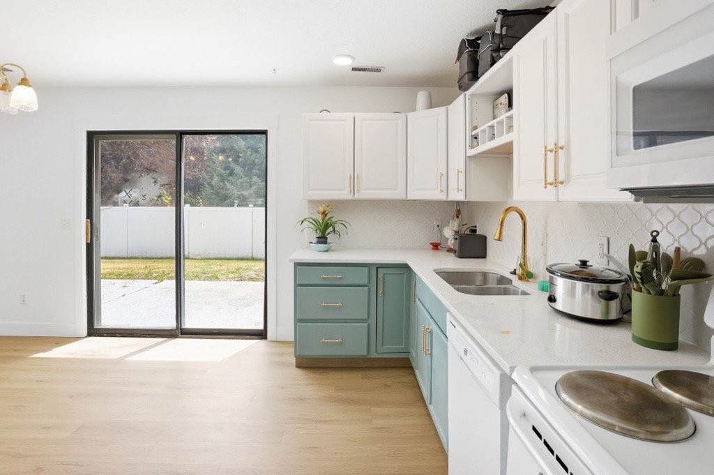Modern kitchen featuring two-tone cabinetry, white countertops, and a decorative tile backsplash