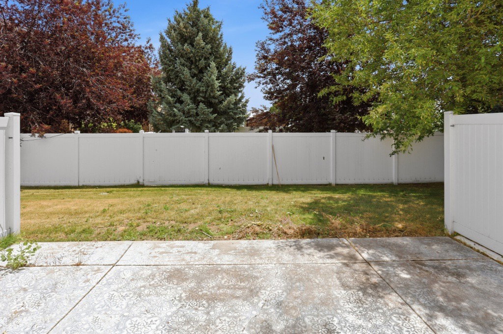 Private backyard featuring a concrete patio, vinyl fencing, and mature trees