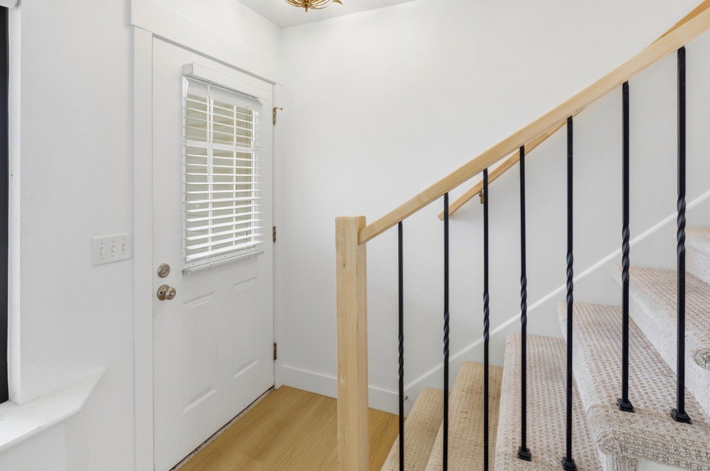 Staircase with light wood handrail and black metal balusters