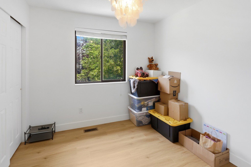 Bright interior room featuring wood-finish flooring, a contemporary ceiling light fixture, and a window offering natural light and exterior greenery