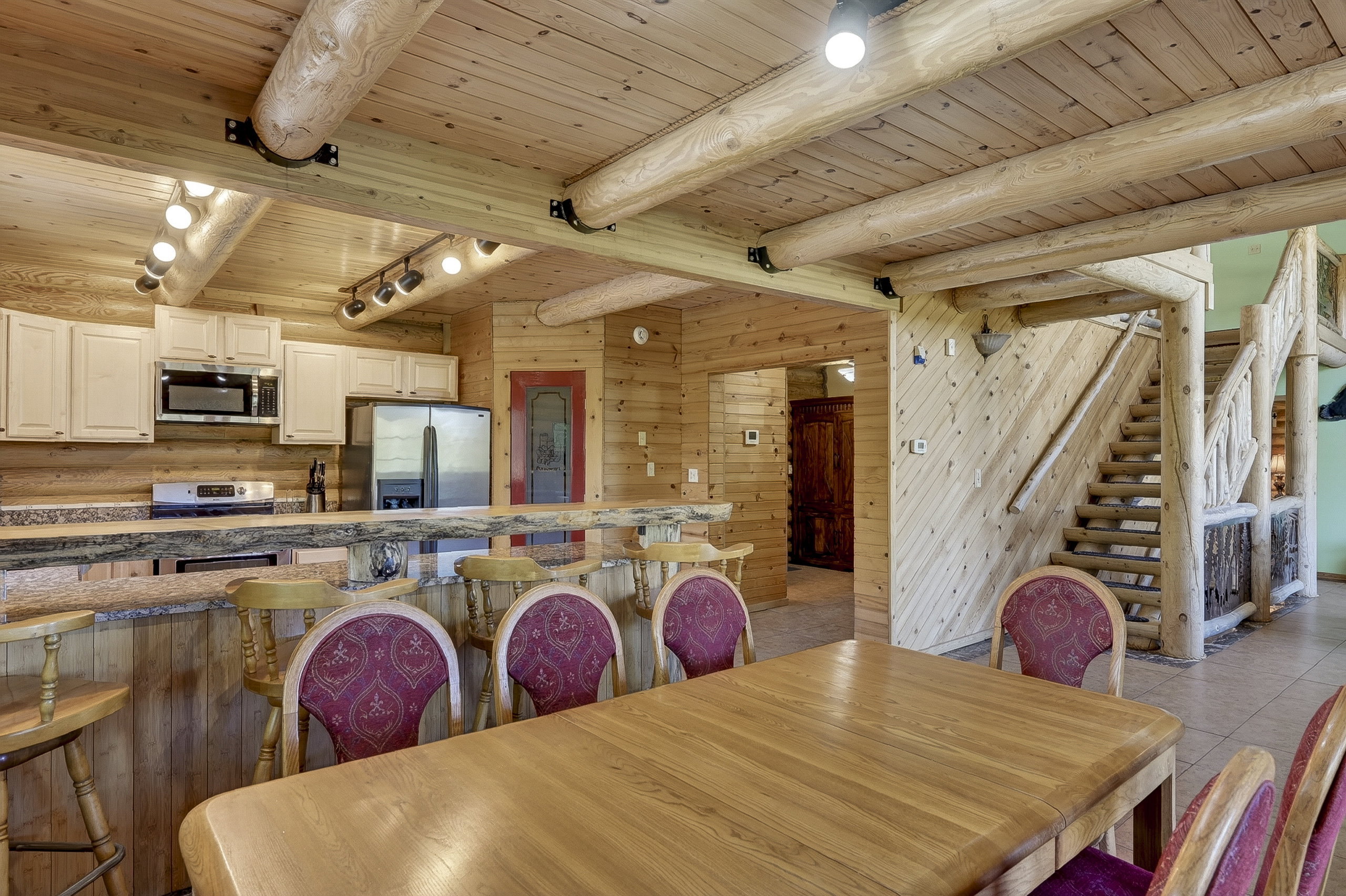 Open-concept living area featuring extensive wood-finish walls and ceilings with exposed log beams