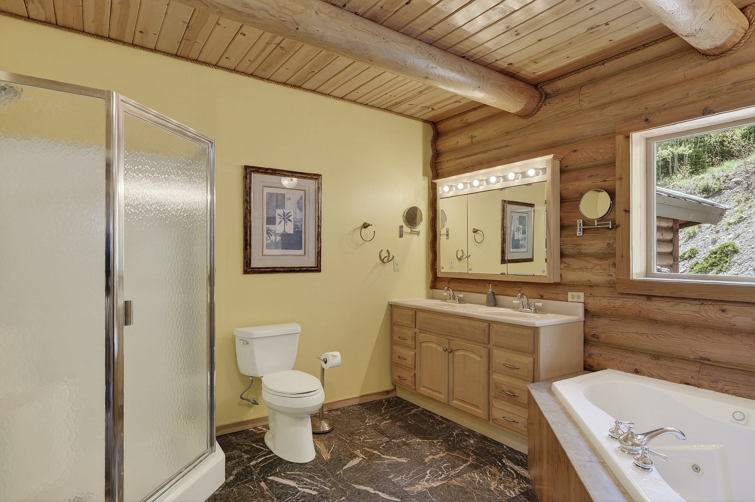 Bathroom featuring log walls and a planked wood ceiling