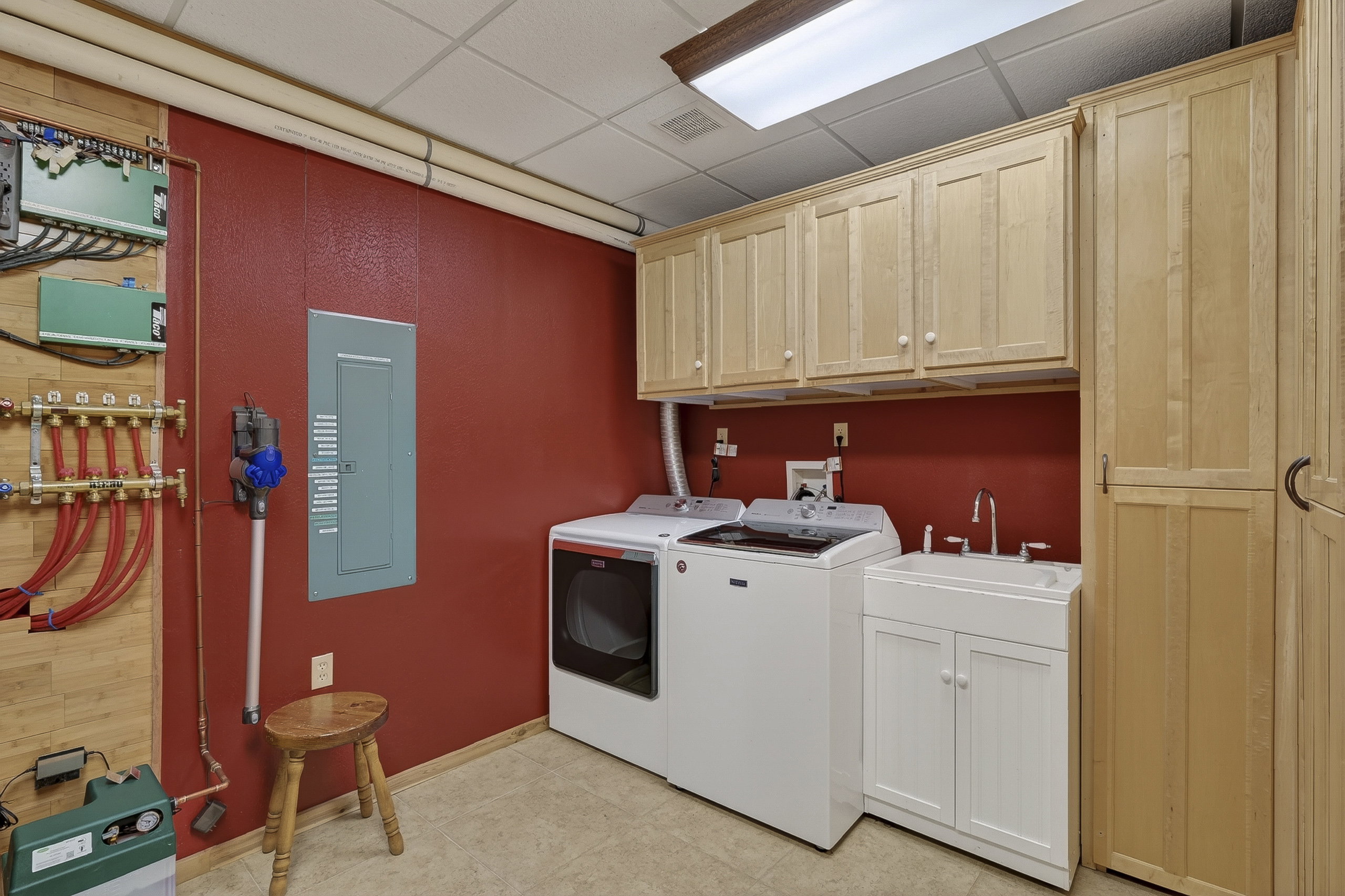 Laundry area featuring upper and lower cabinetry, a utility sink with a chrome faucet, and tile flooring