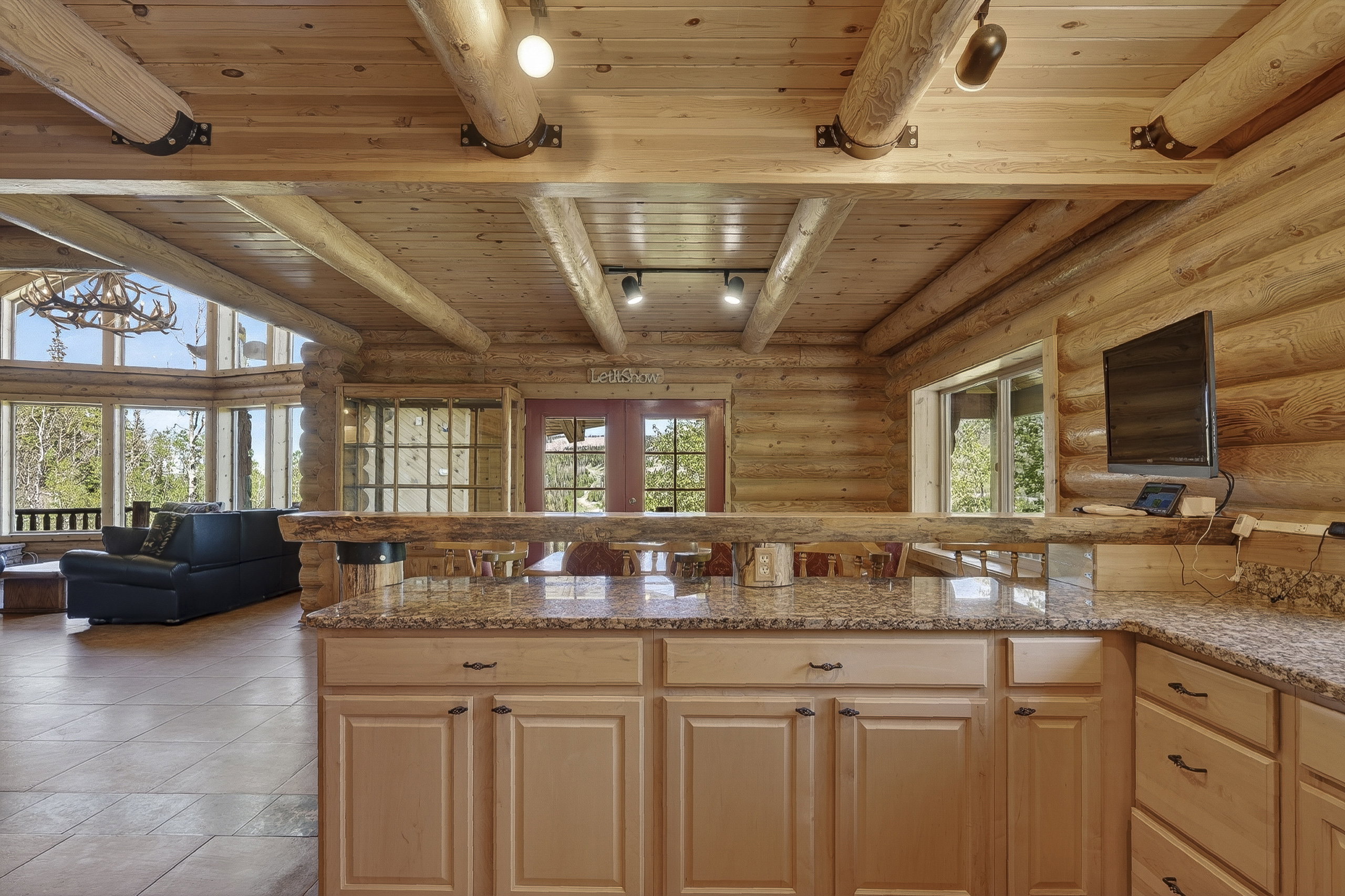 Kitchen featuring granite-style countertops, light wood cabinetry, and a natural wood breakfast bar