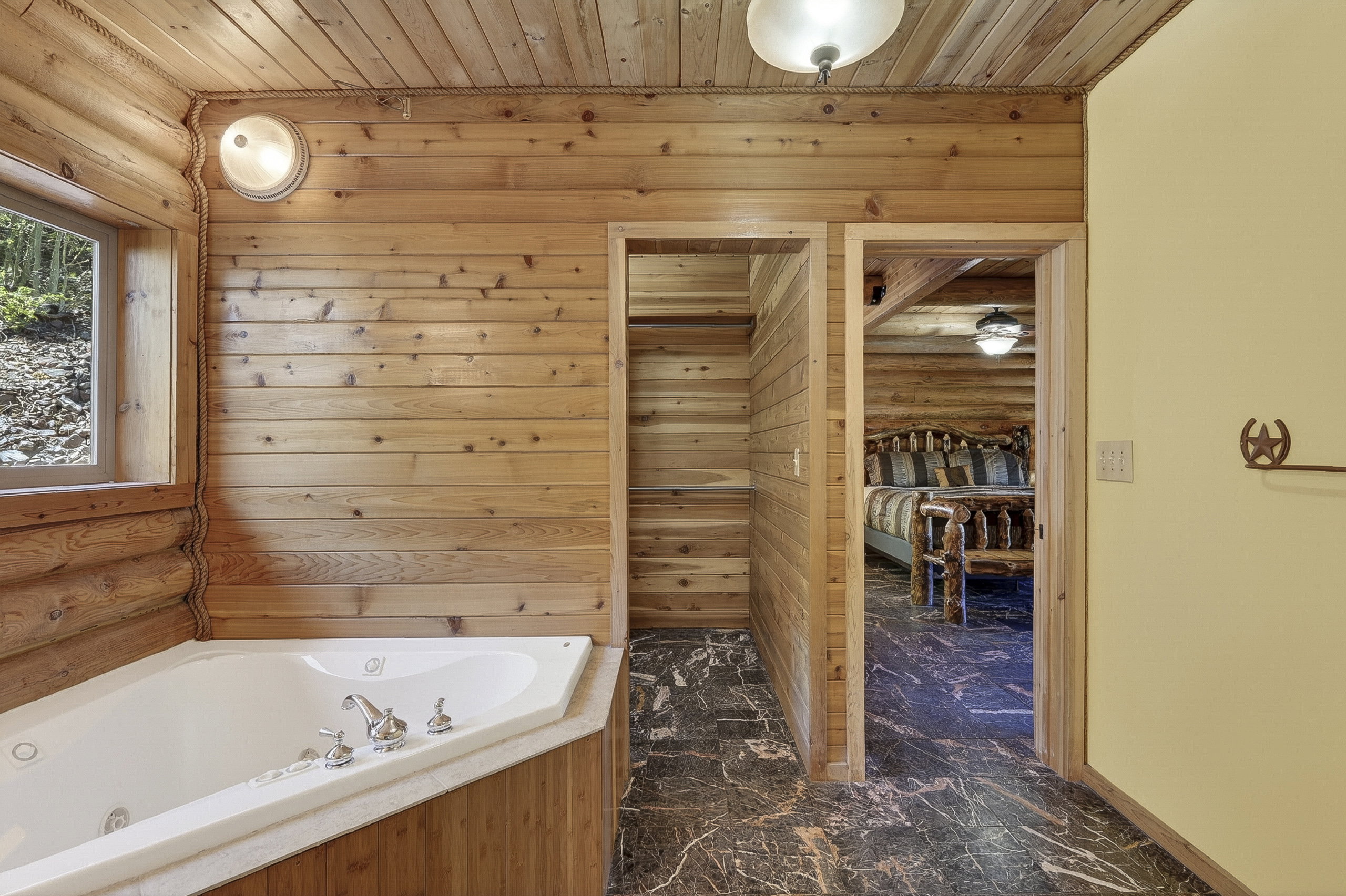 Corner jetted tub with chrome fixtures, surrounded by natural wood paneling