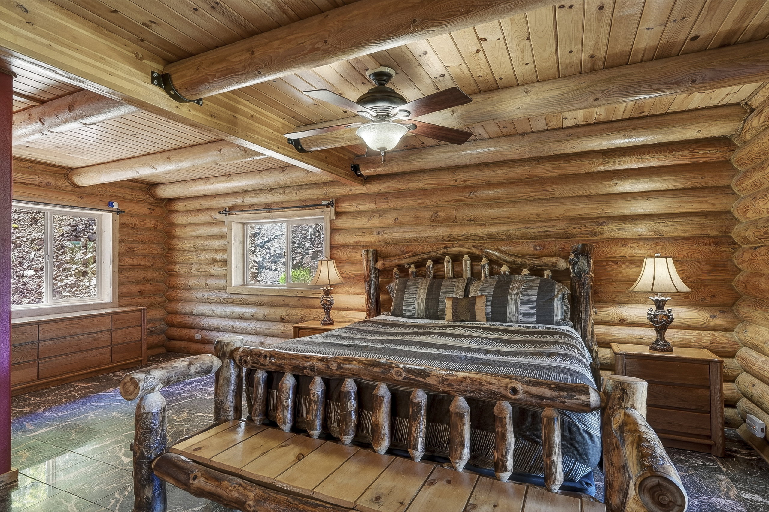 Rustic wood-paneled room featuring log walls, exposed log ceiling beams, and wood-paneled ceilings