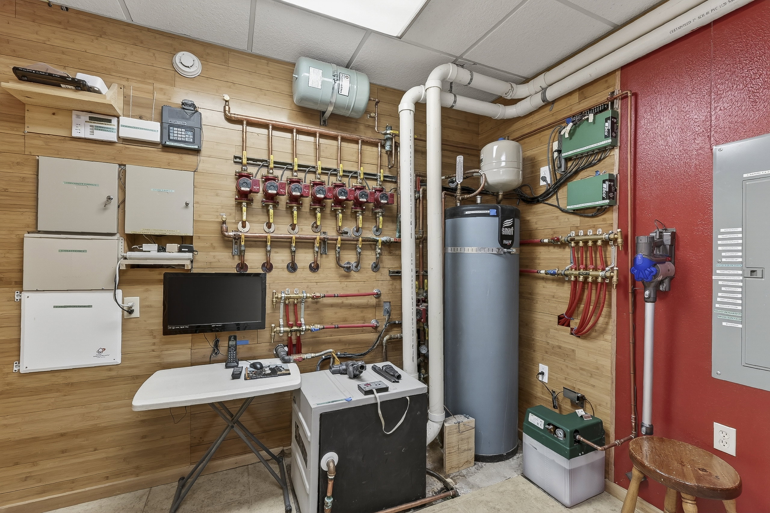 Utility room featuring a water heater, extensive plumbing, and electrical panels