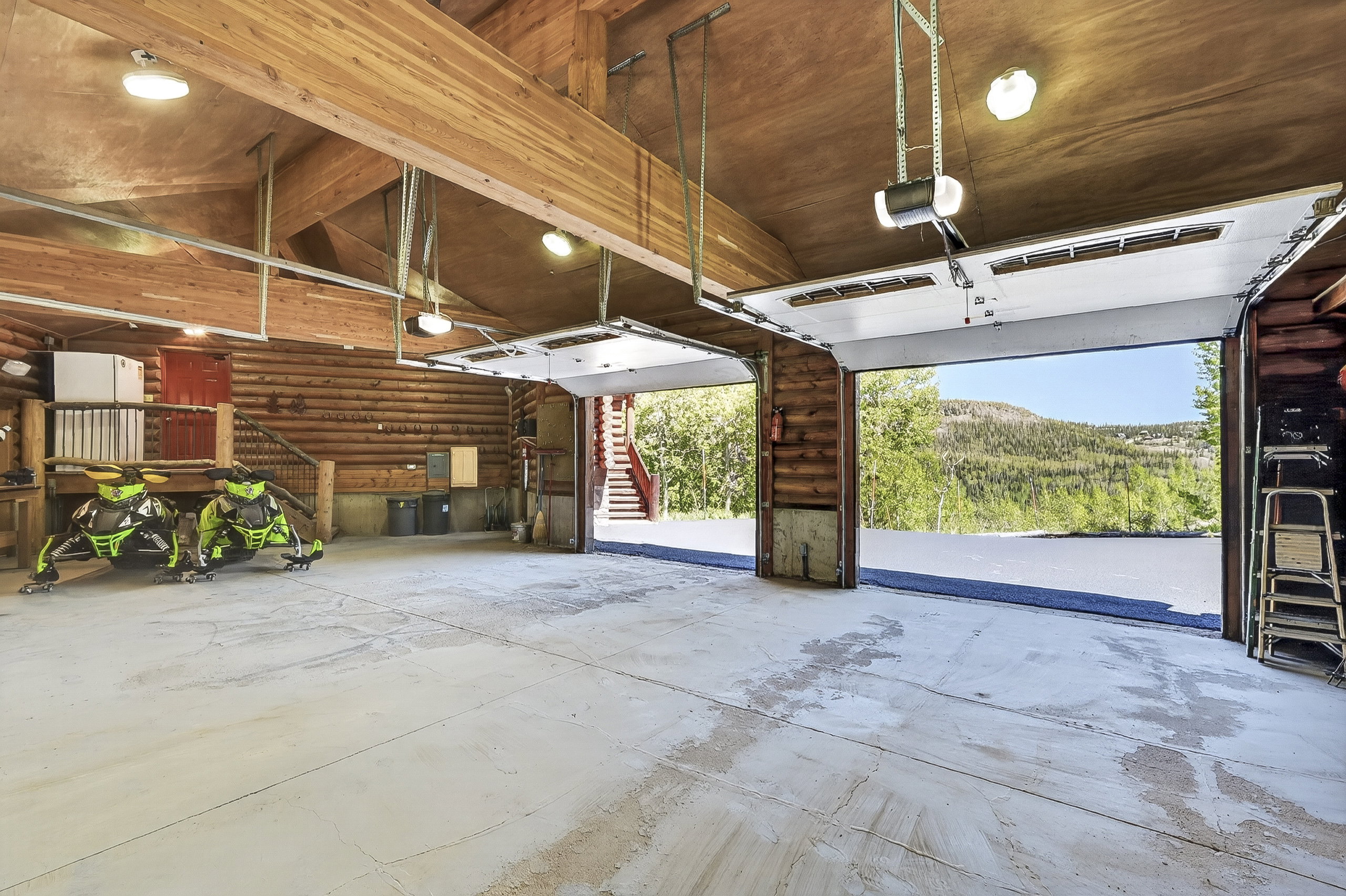 Spacious garage featuring exposed wood beam construction, durable concrete flooring, and multiple automatic garage doors