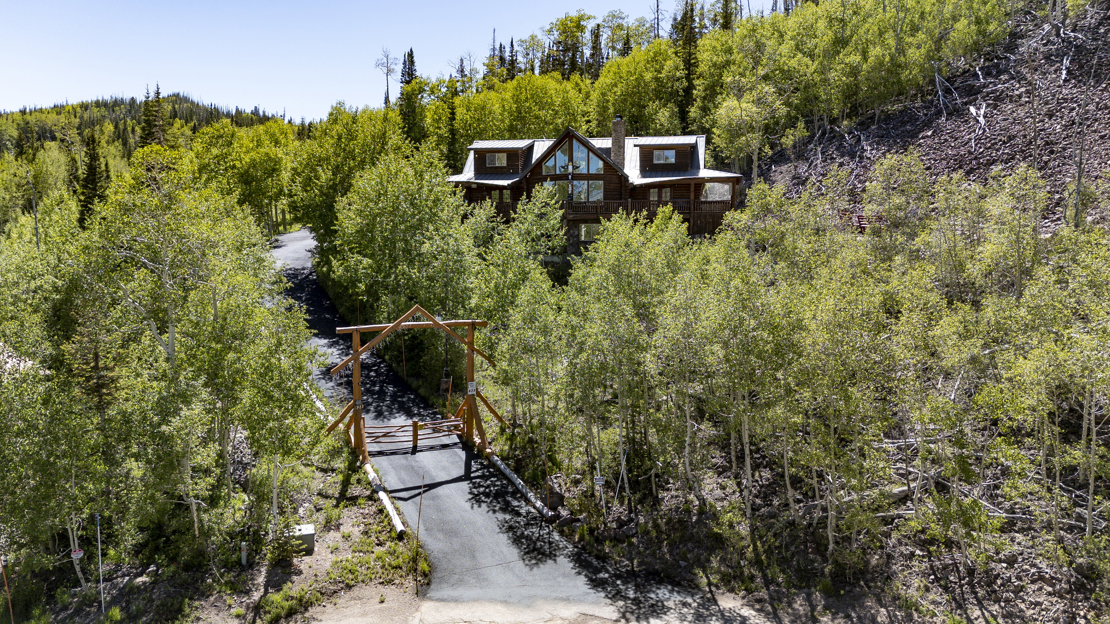 Mountain retreat featuring a log cabin aesthetic, a gabled roof, and extensive natural landscaping
