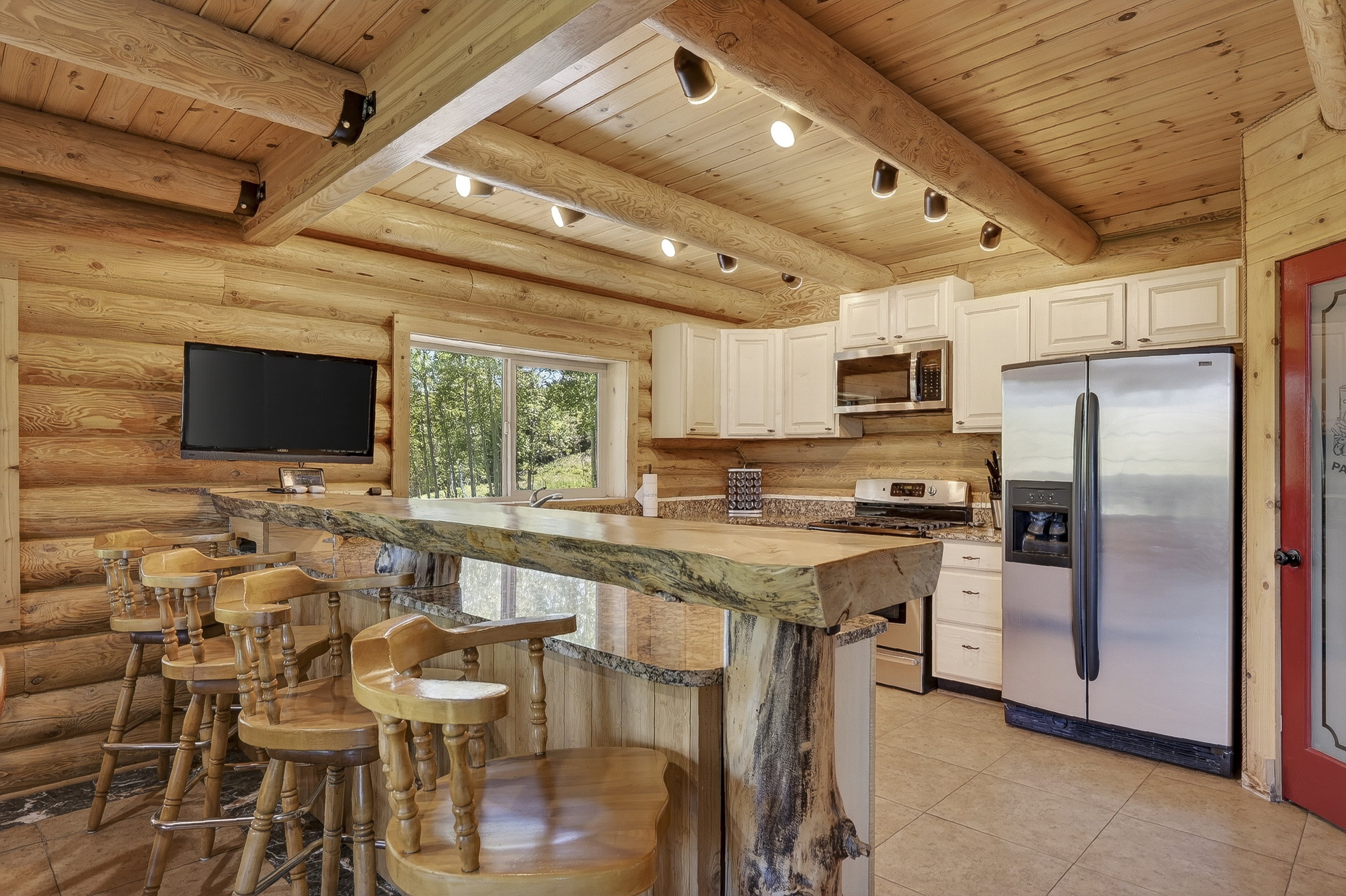 Kitchen featuring natural log walls, wood-finish ceiling, and exposed log beams