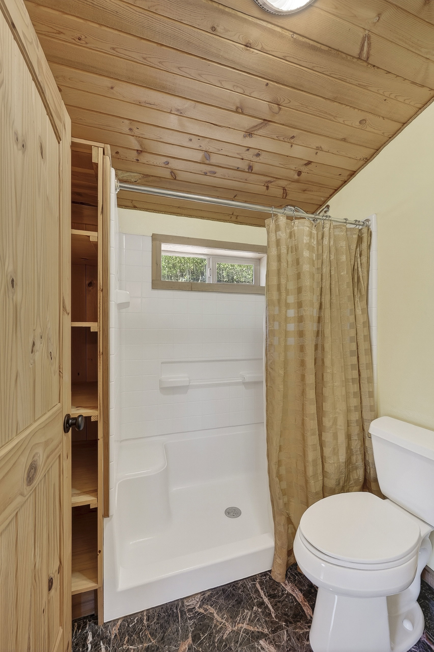 Three-piece bath with a white shower stall, a white toilet, and dark marble-patterned flooring