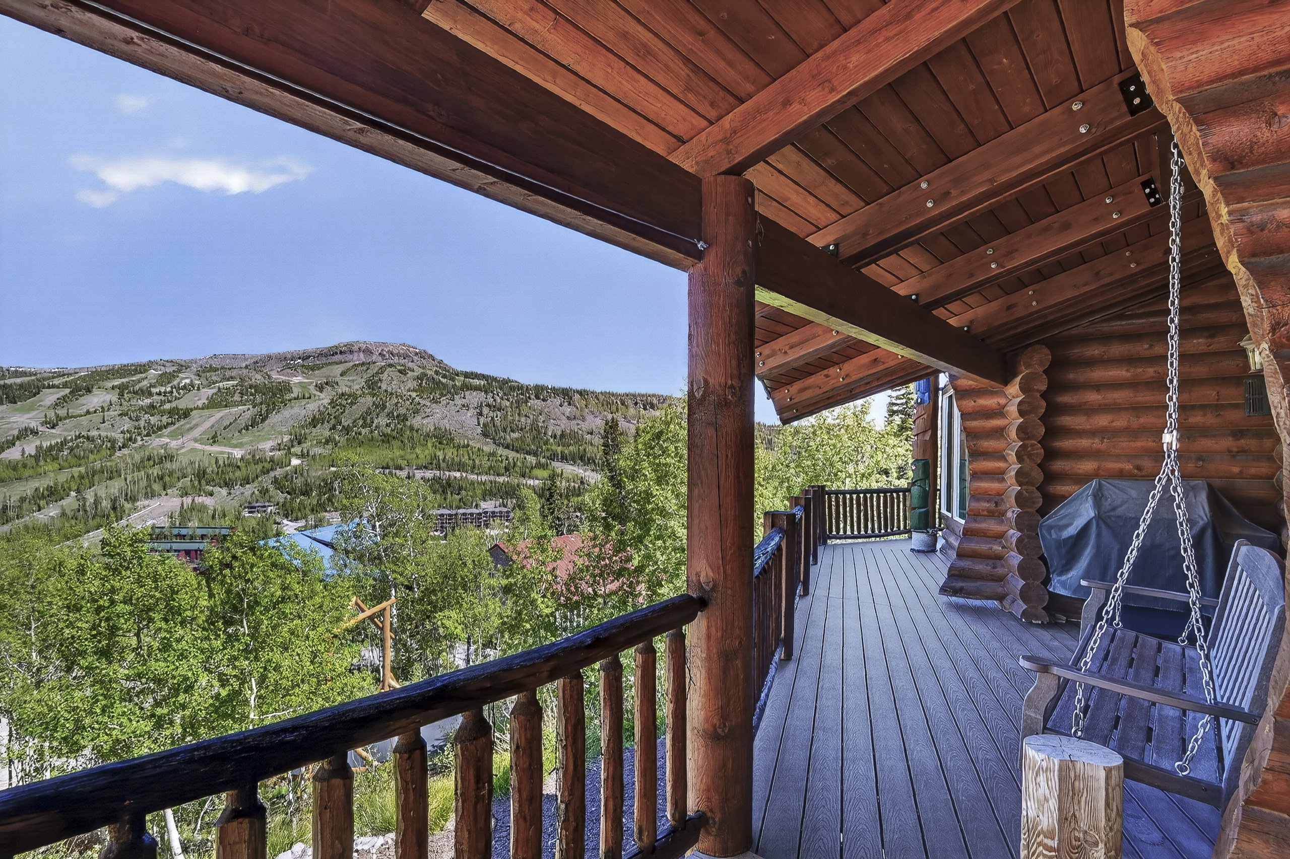Expansive log cabin-style deck featuring natural wood-finish flooring, exposed wood beams, and a railing system