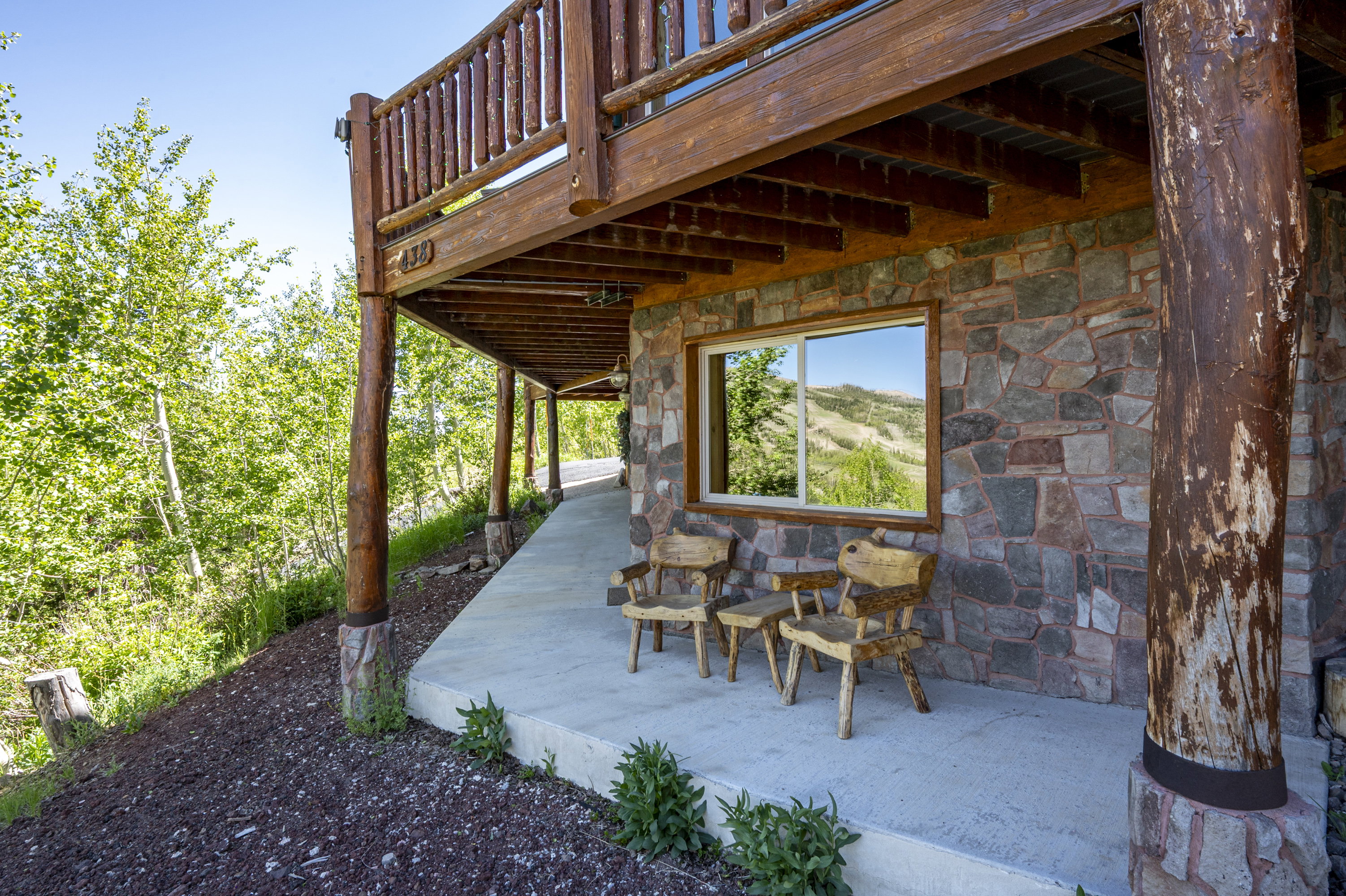 Stone veneer exterior with a concrete patio featuring natural wood support columns