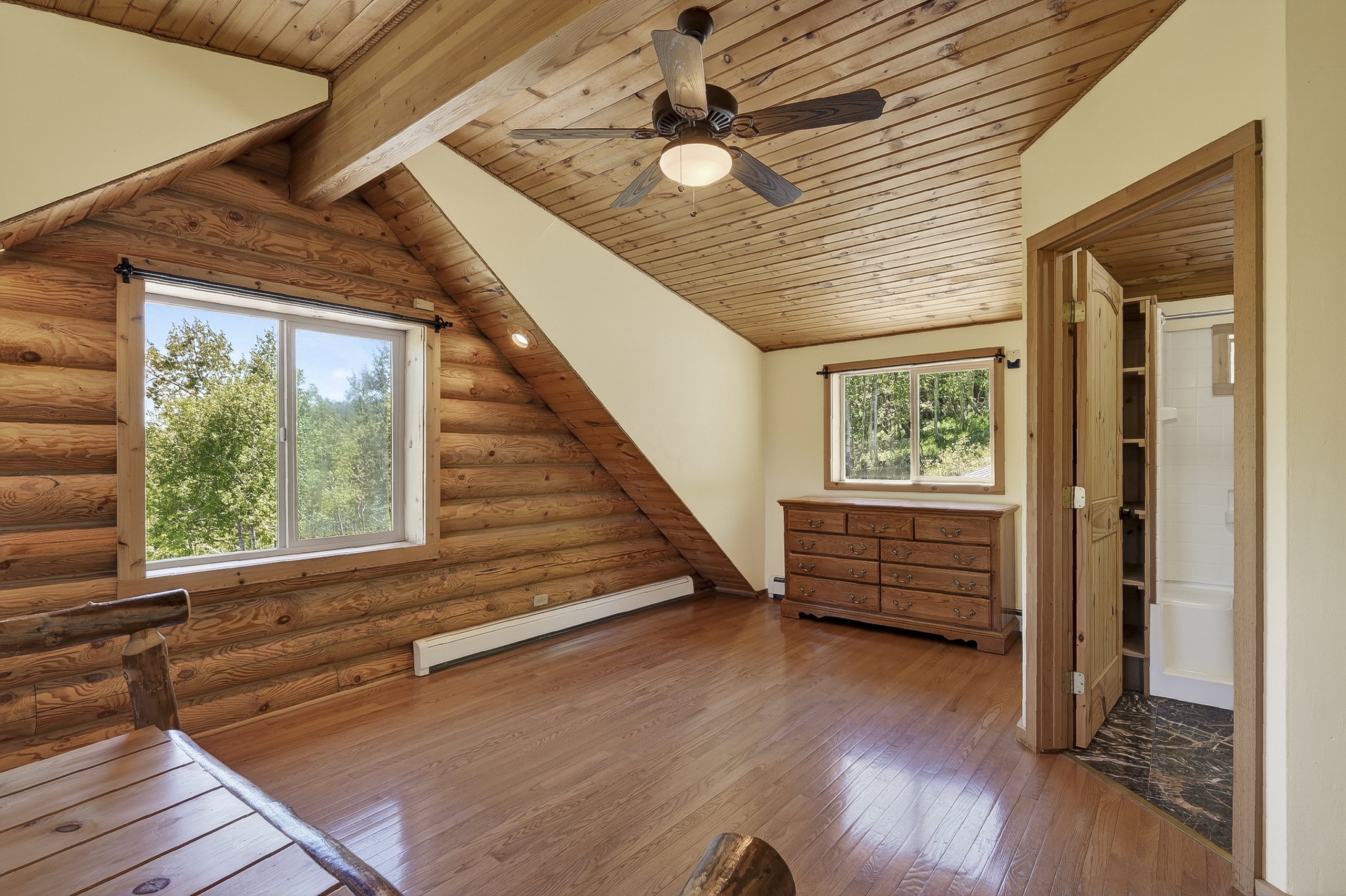 Spacious room featuring log-style walls and wood-finish flooring