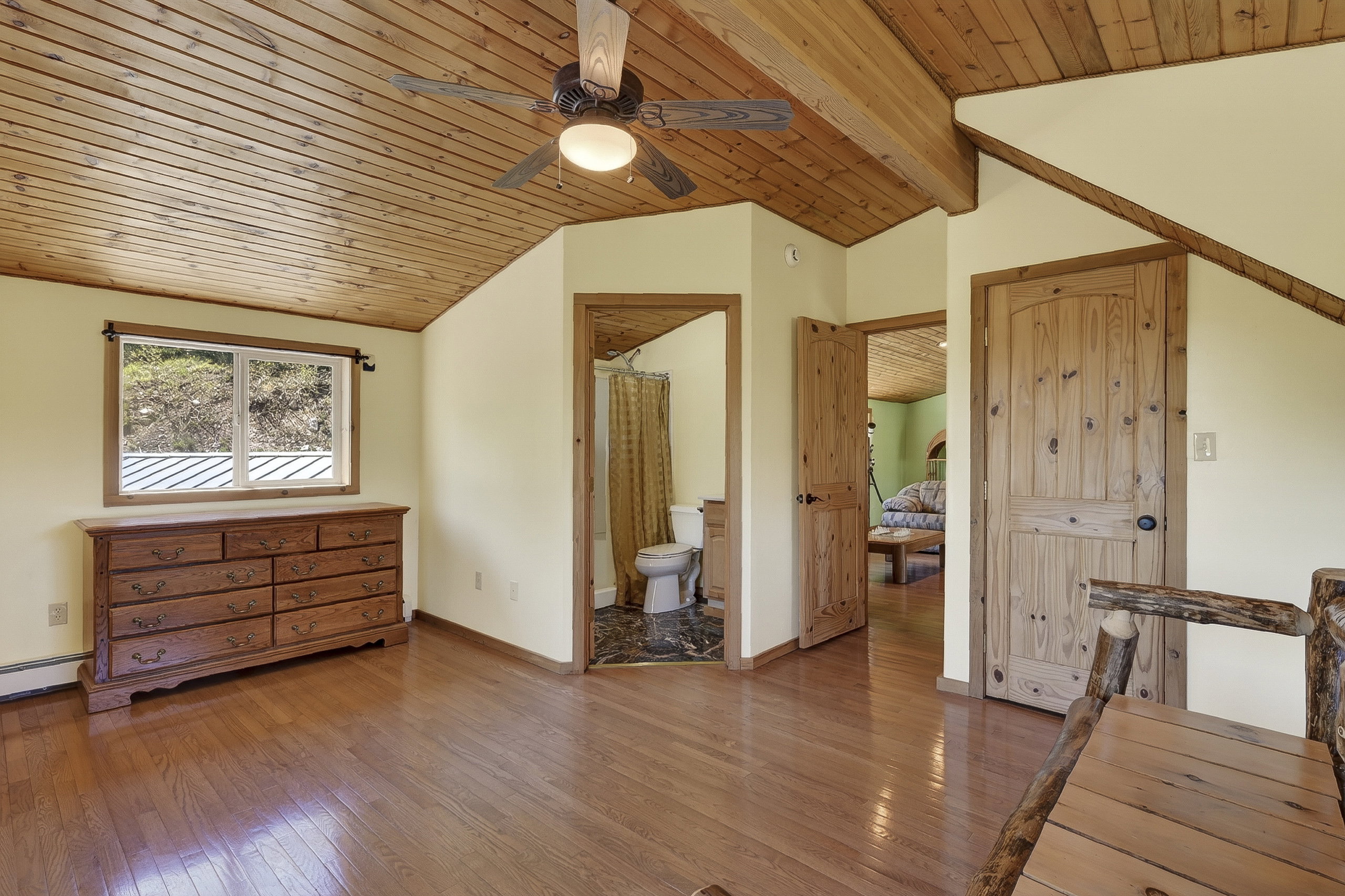 Vaulted wood-paneled ceiling with exposed beams and a ceiling fan
