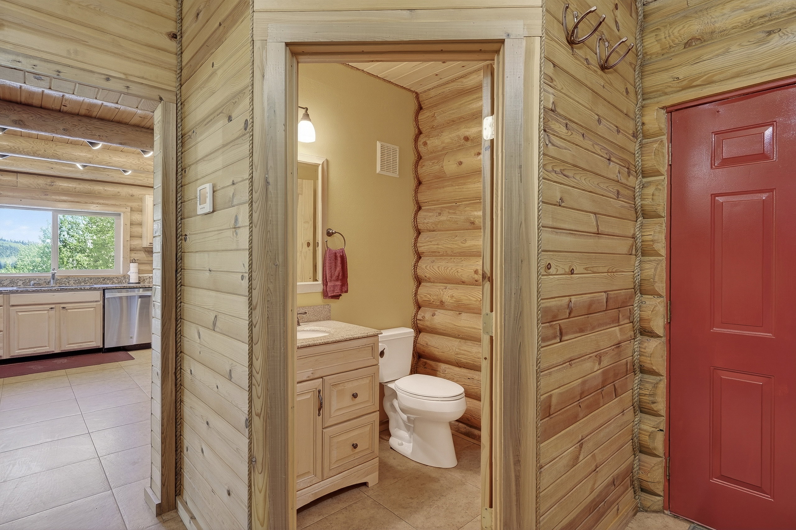 Bathroom featuring a light wood-finish vanity with a light-colored countertop, a wall-mounted light fixture, and a toilet
