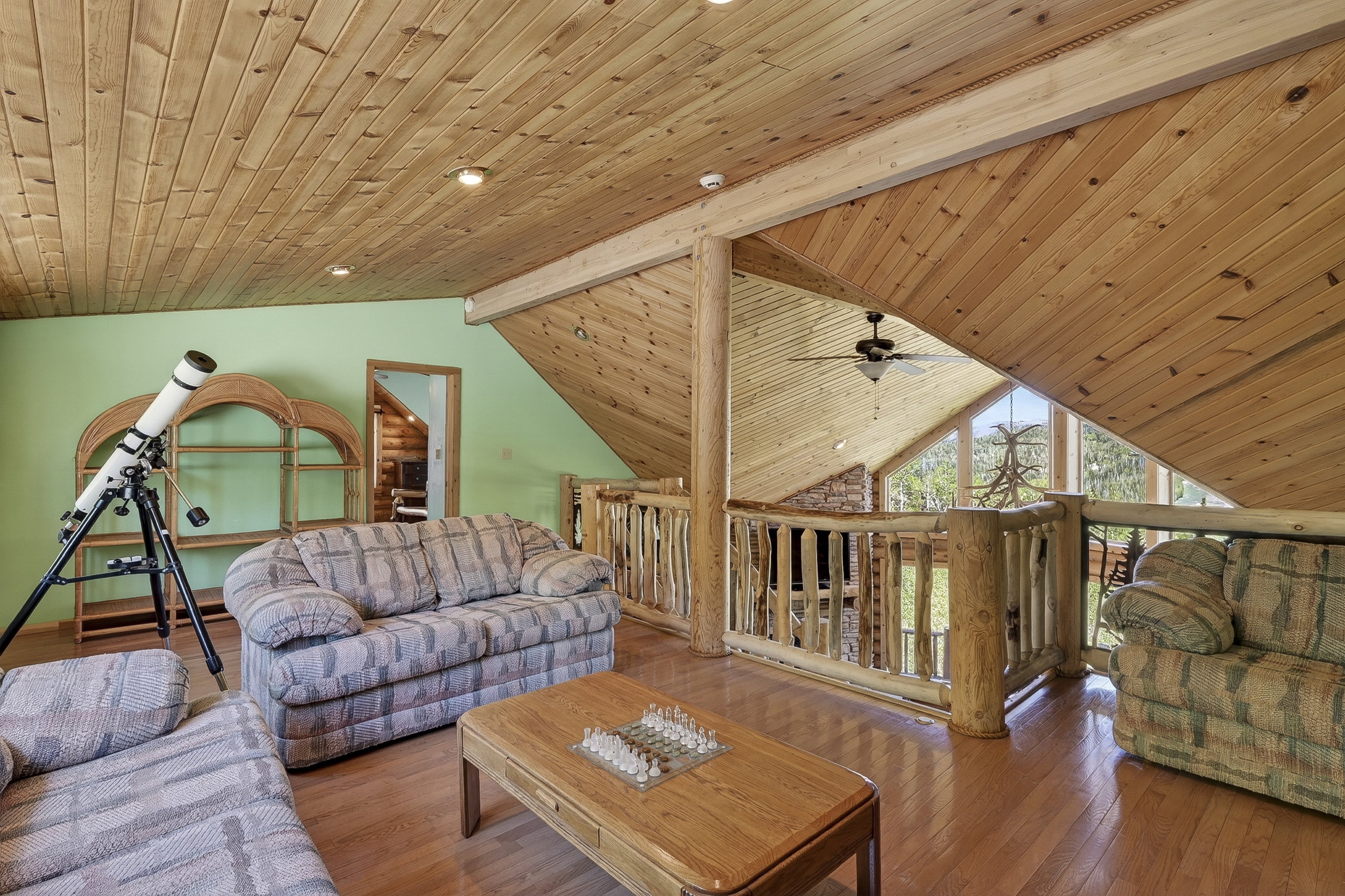 Expansive loft area featuring wood-finish flooring, a full wood plank ceiling, and a rustic log railing overlooking the space below