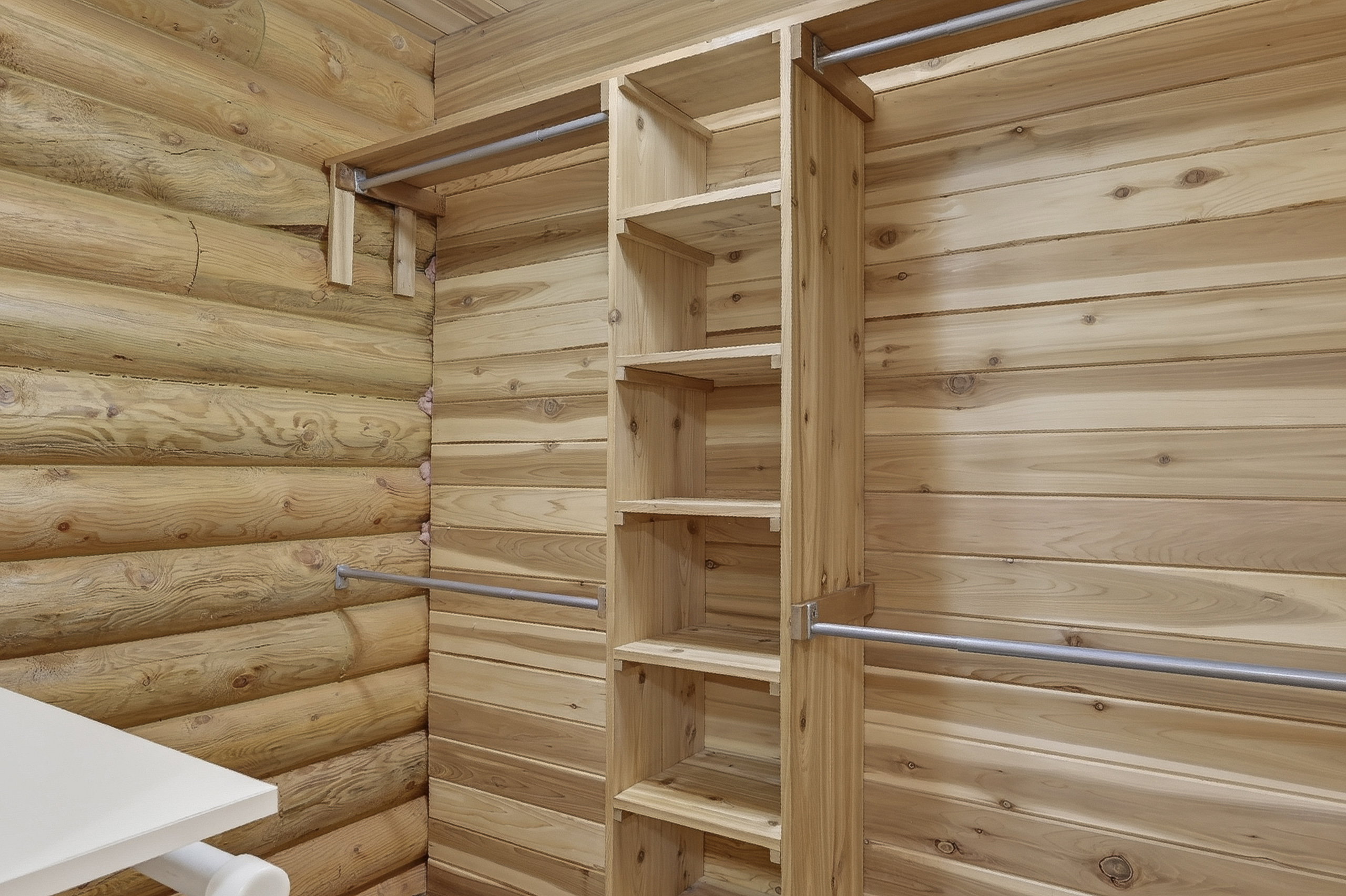 Custom wood shelving system and hanging rods in a wood-paneled space