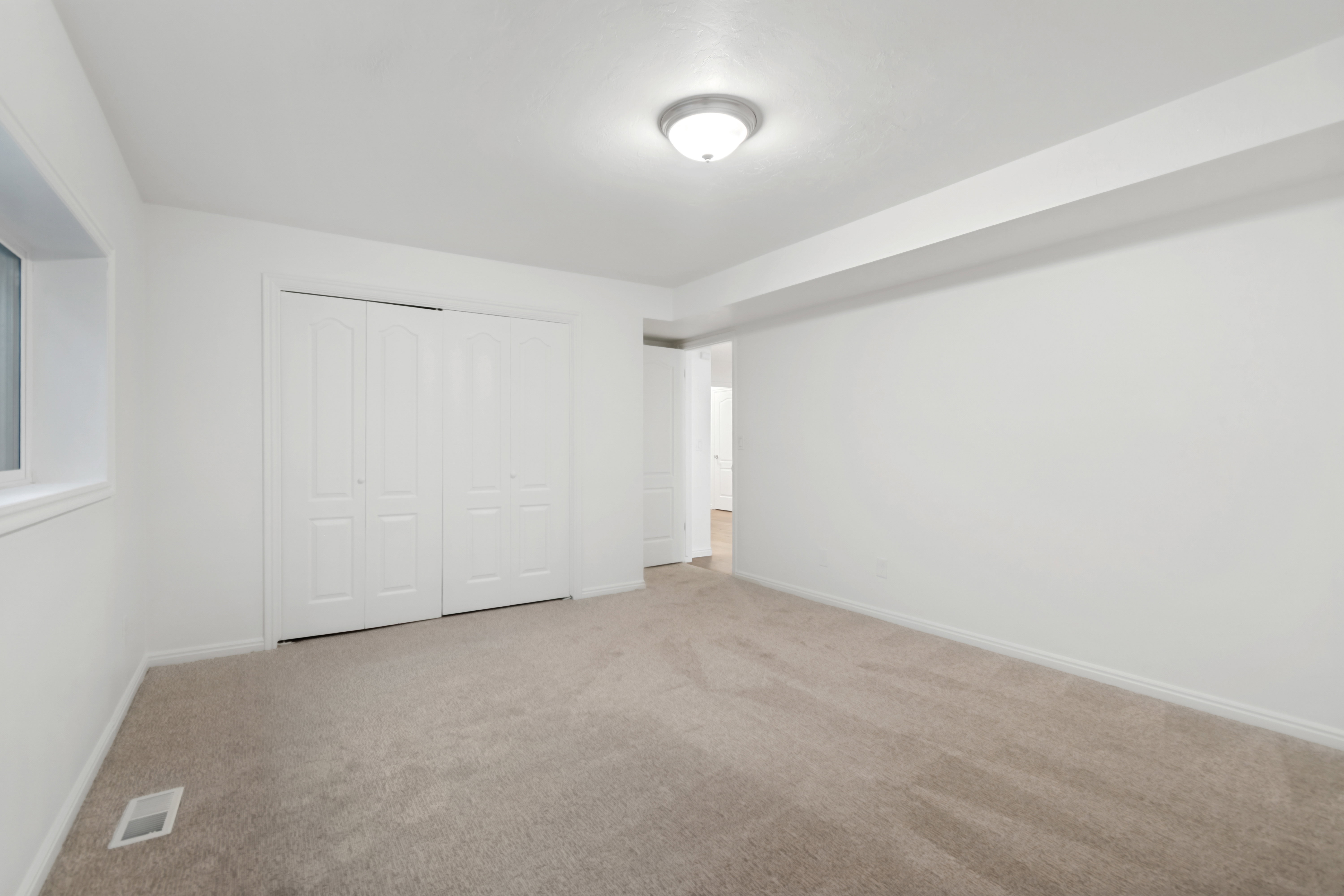 Carpeted room featuring a ceiling-mounted light fixture, white walls, and bi-fold closet doors