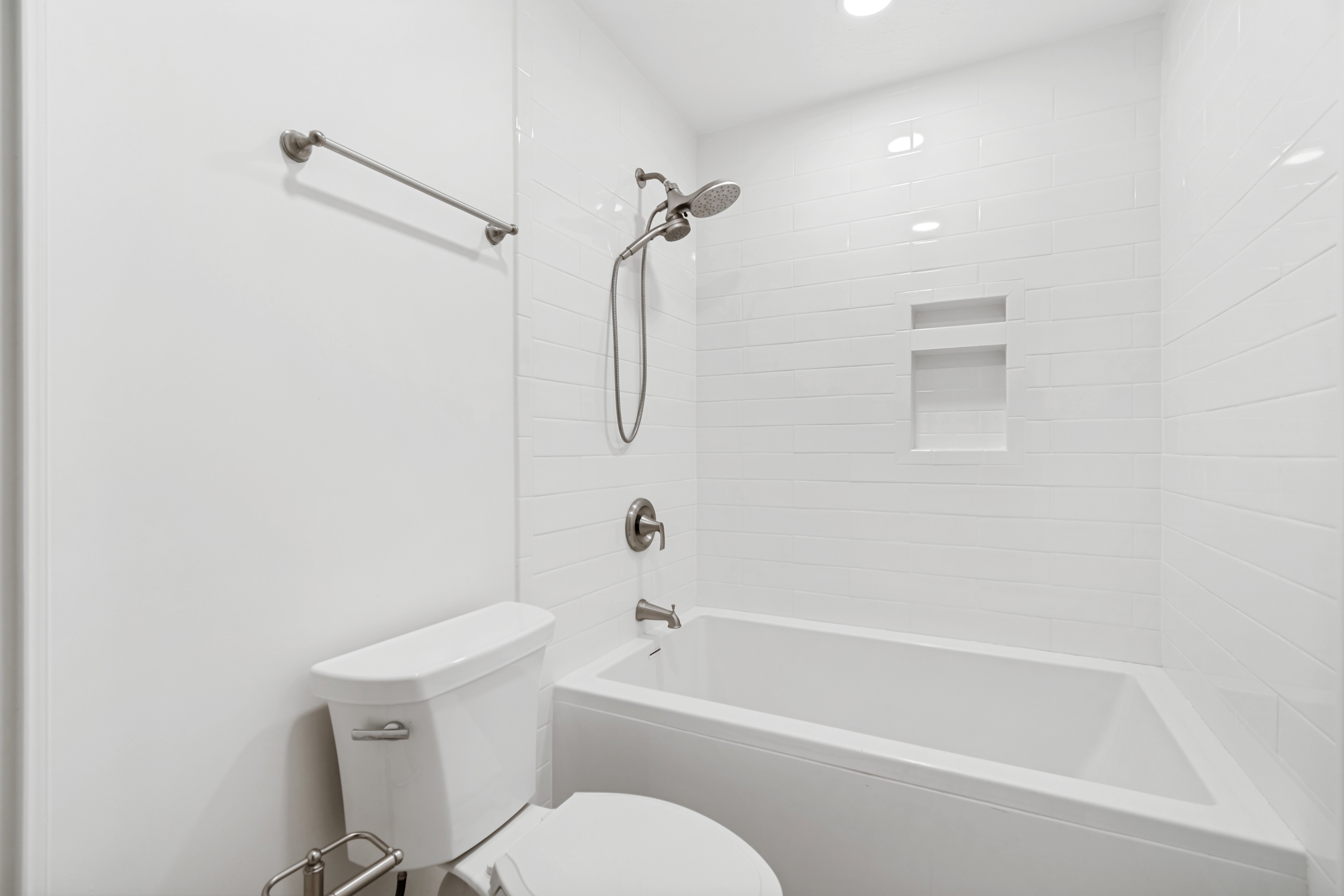Bathroom featuring a white subway tile surround, recessed lighting, and a built-in shower niche